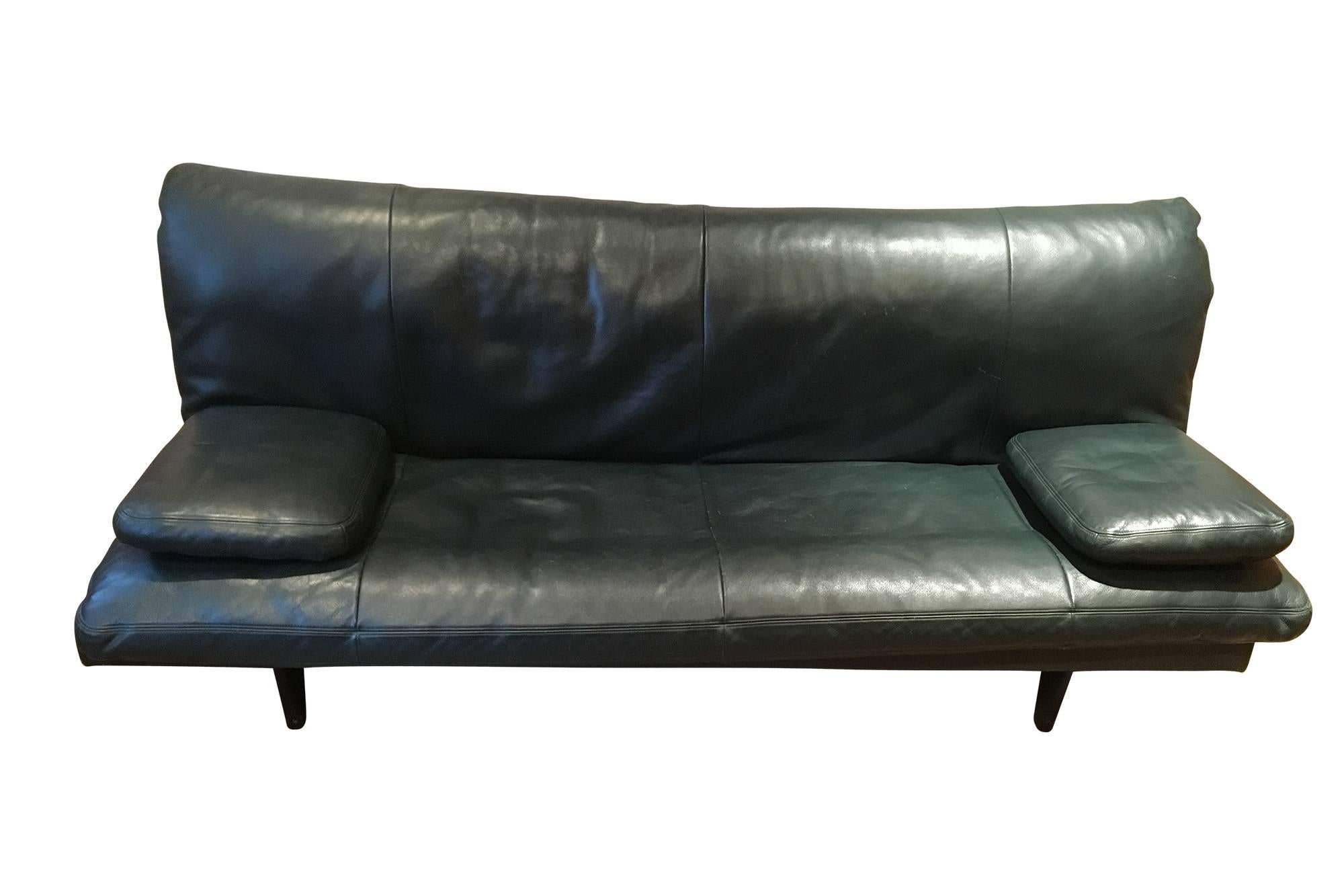A handsome sofa or daybed by Ernst Ambühler for De Sede, circa 1970s. Cleverly designed to easily convert from a sofa to a double-size bed. Featuring high quality hunter green leather upholstery with a removable mattress cushion and two loose