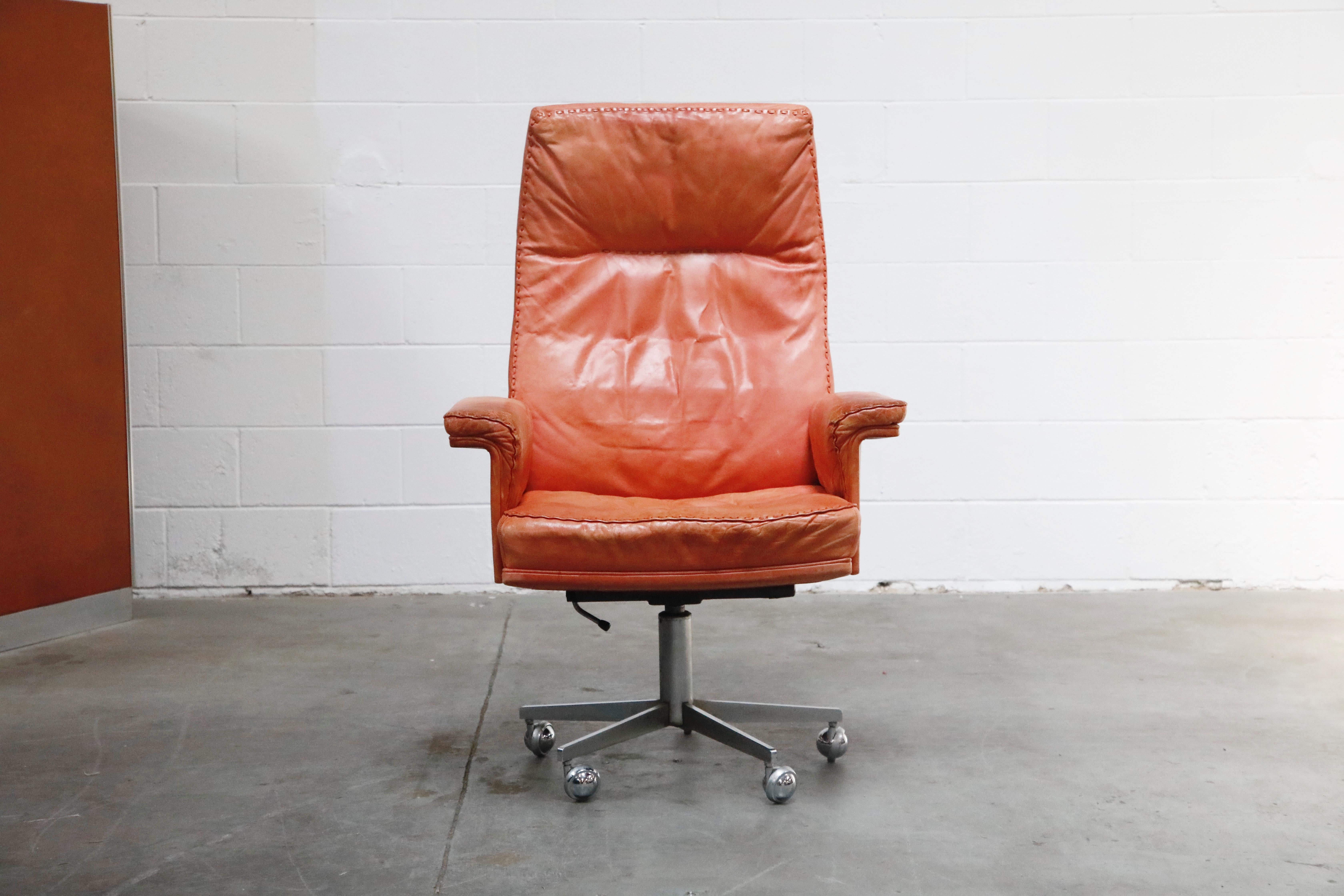 Beautiful distressed leather on this vintage De Sede DS35 highback executive desk chair on casters. This incredible office chair features an extremely comfortable form, burnt orange color aniline leather upholstery with whipstitch edge detail,