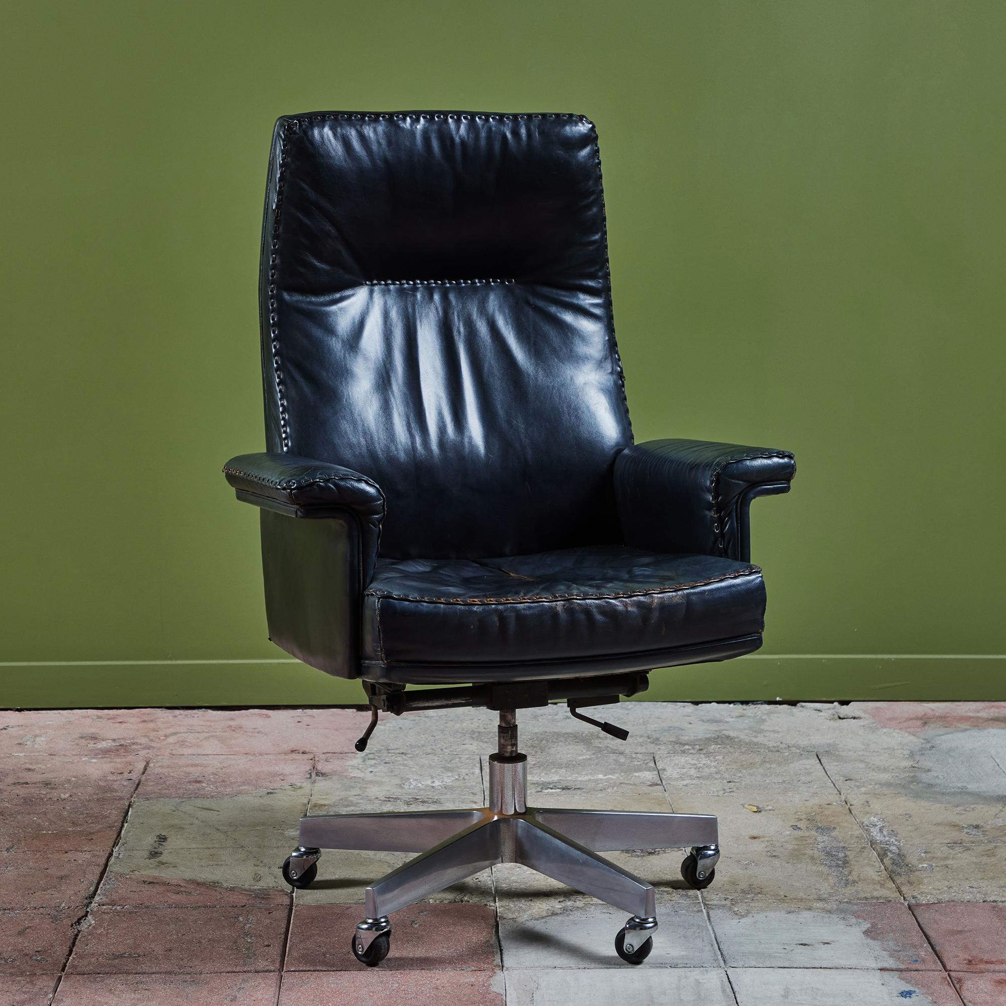 Executive desk chair by De Sede c.1970s. This Swiss made chair features the original black leather upholstery with a beautiful hand stitched detailing along the edge. The chair is outfitted with a tilt swivel mechanism that allows the seat to be