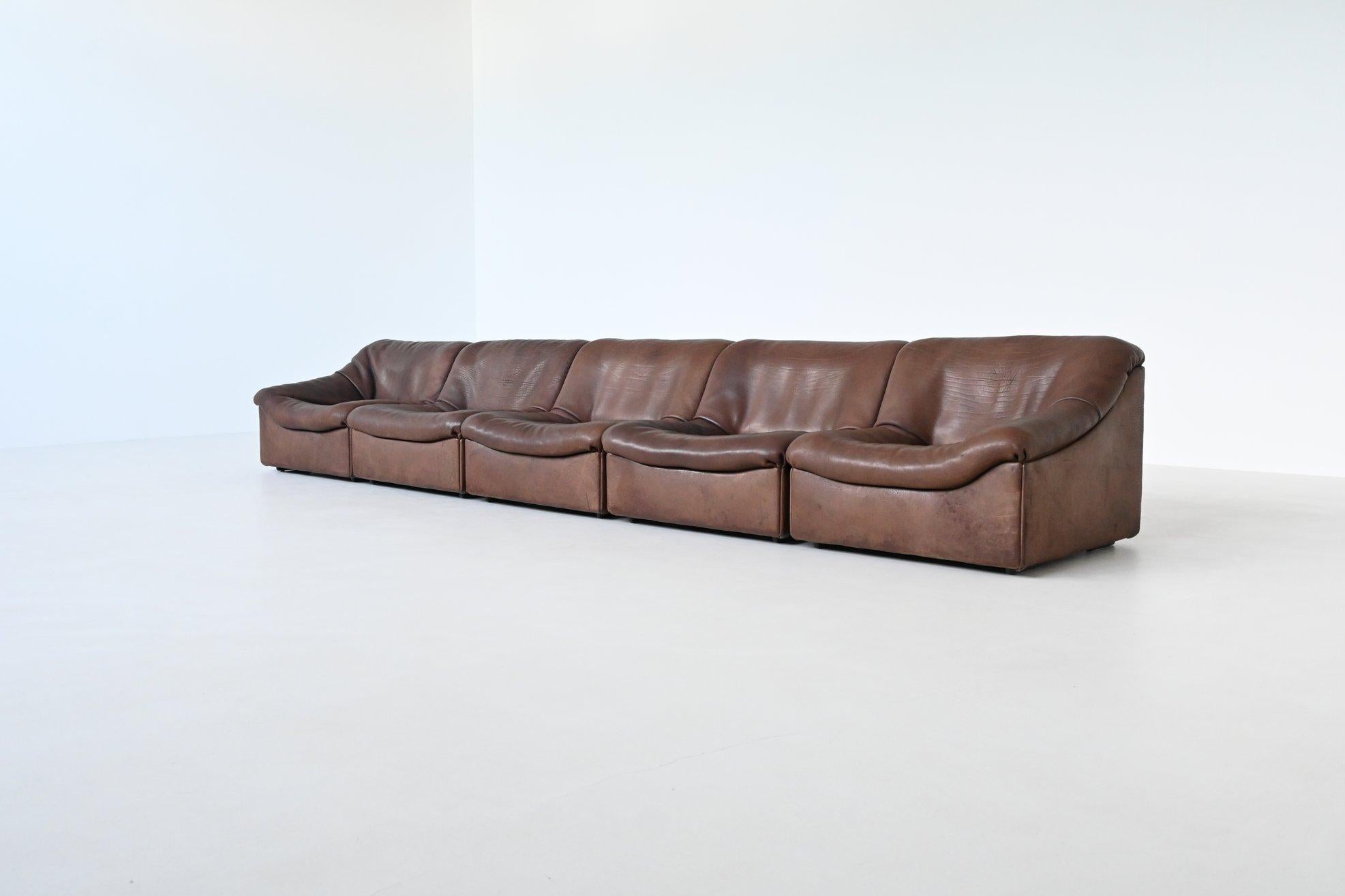 Icónico sofá seccional modelo DS 46 diseñado y fabricado por De Sede, Suiza 1970. Compuesto de grueso cuero de búfalo marrón, este conjunto incluye cinco elementos modulares, con dos piezas finales, que permiten varias configuraciones para adaptarse