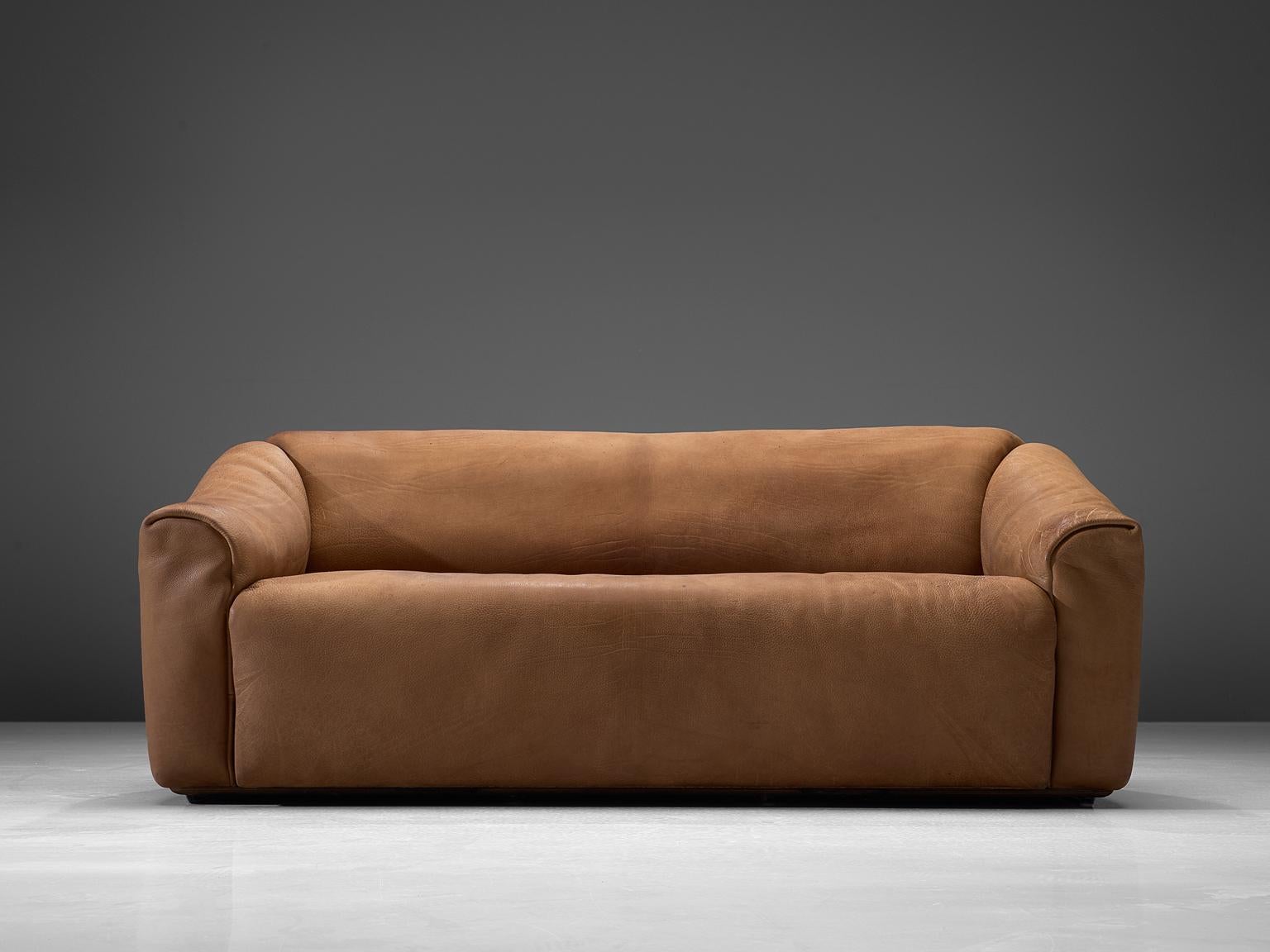 Highly comfortable DS47 sofa in light cognac leather by De Sede. The design is simplistic, yet very modern. A tight and cubic outside with a soft and curved inside, which emphasize the comfortable character of this set. The thick leather is laid in