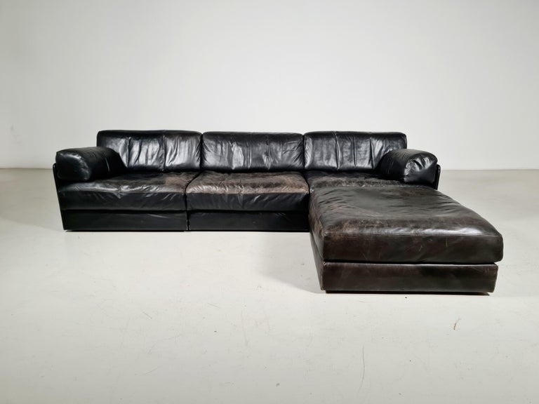 Beautiful 3-piece black leather modular sofa with ottoman by De Sede from the 1970s. The sofa can be converted into a guest bed in just a few simple steps. Extremely comfortable with a nice patina. Many different settings are possible.

Beautiful