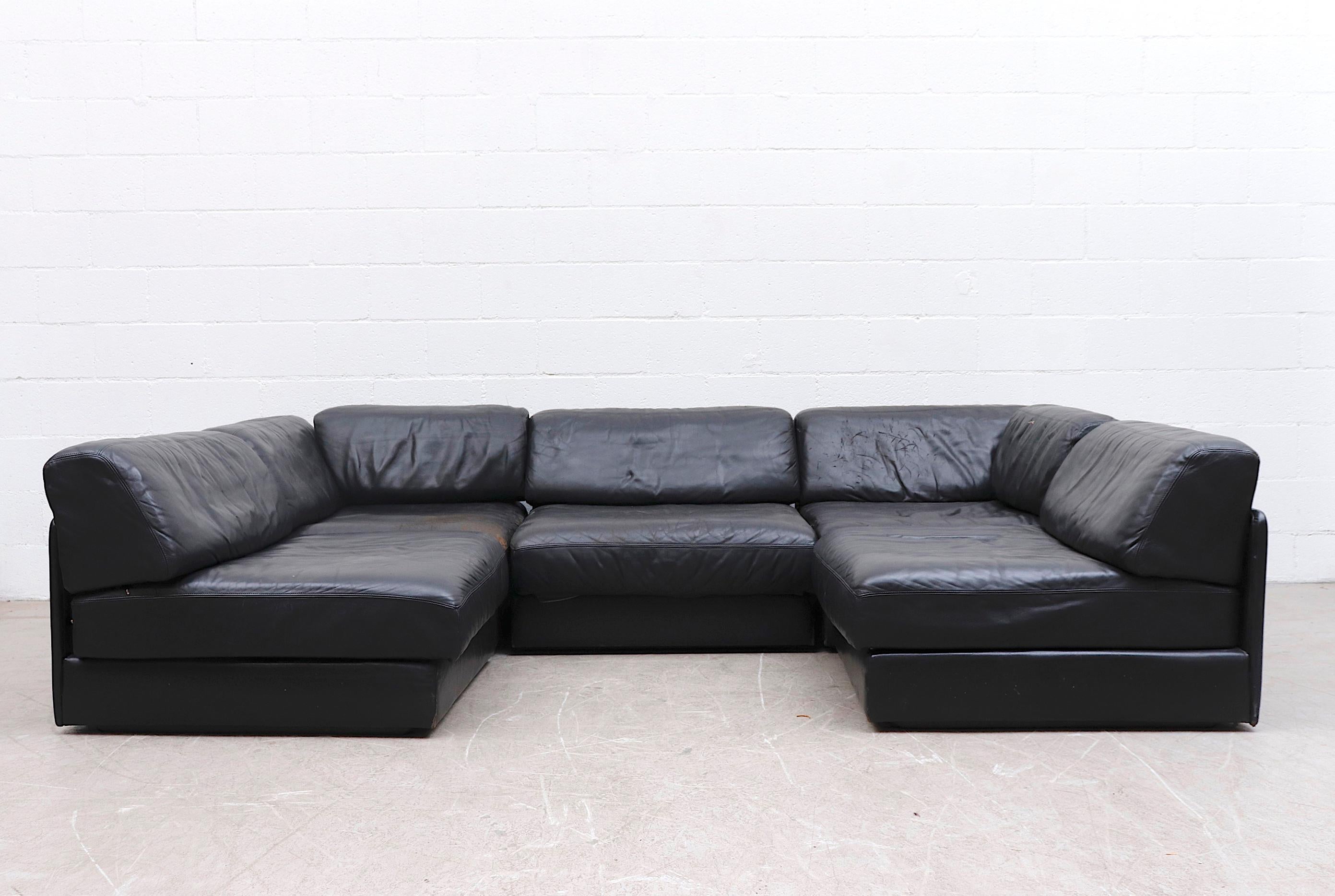 Handsome De Sede DS 76 black leather 5 piece sectional sleeper sofa with deep zip-on cushions that fold out to beds. A few well loved sections with visible wear and some cracking to seat. A few minor tears. Measurements shown are as seen in 1st