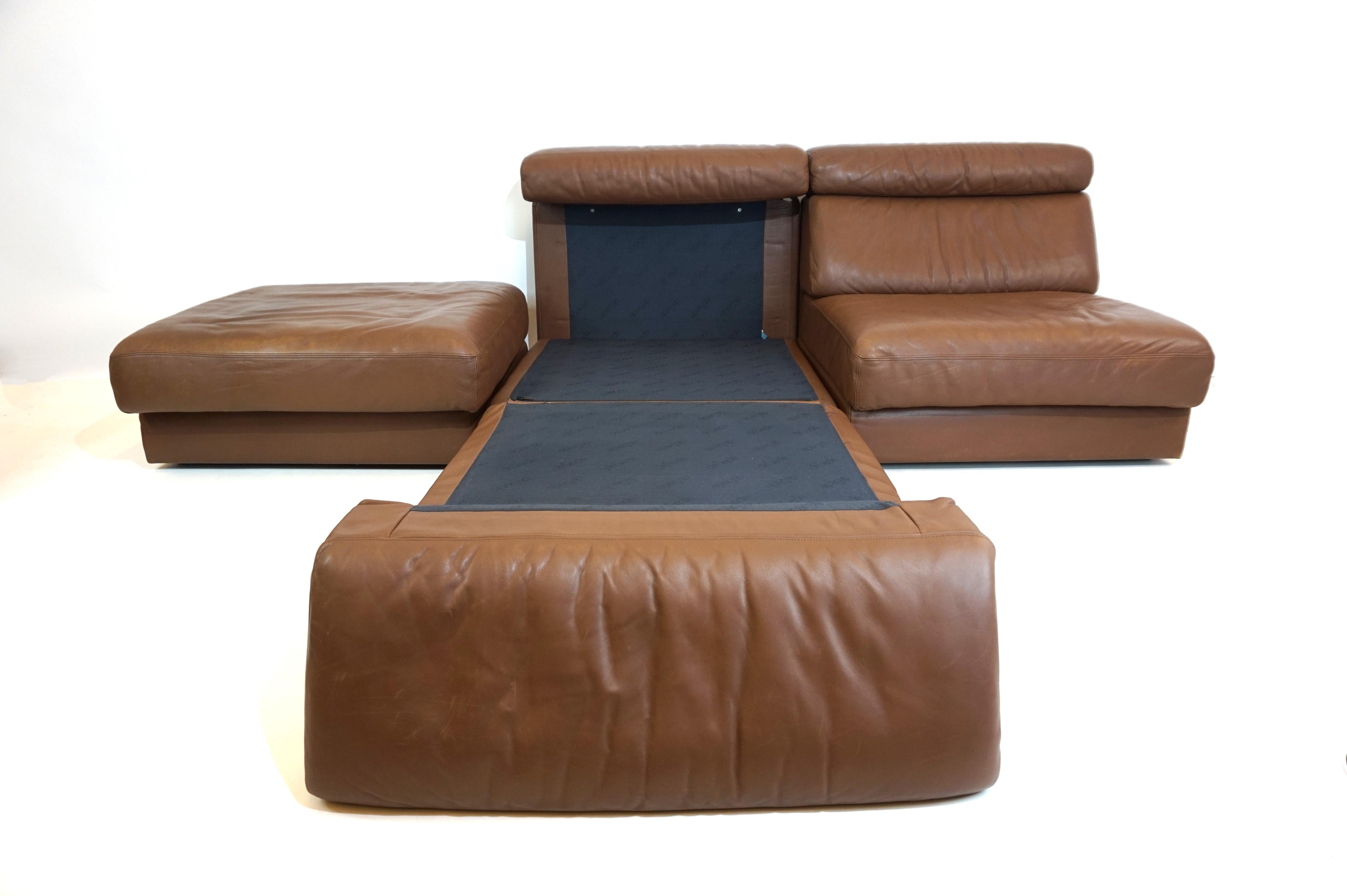 This modular sofa consists of 2 armchairs and a seat cushion, all of which can easily be converted into a comfortable bed. The brown leather of the armchairs and the ottoman is in very good condition, soft and without damage, only minimal signs of