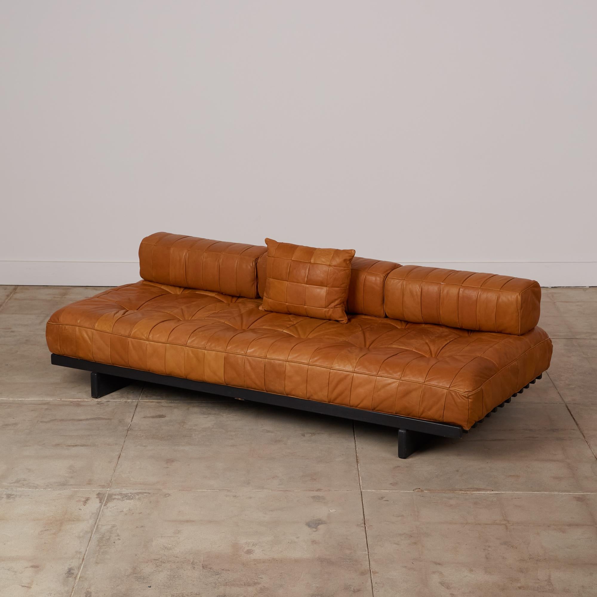 DS 80 leather daybed by De Sede, Switzerland, c.1960s. The daybed features a patinated patchwork leather tufted cushion with three patchwork leather bolster cushions and a single leather throw pillow. The wooden slat frame has an ebonized
