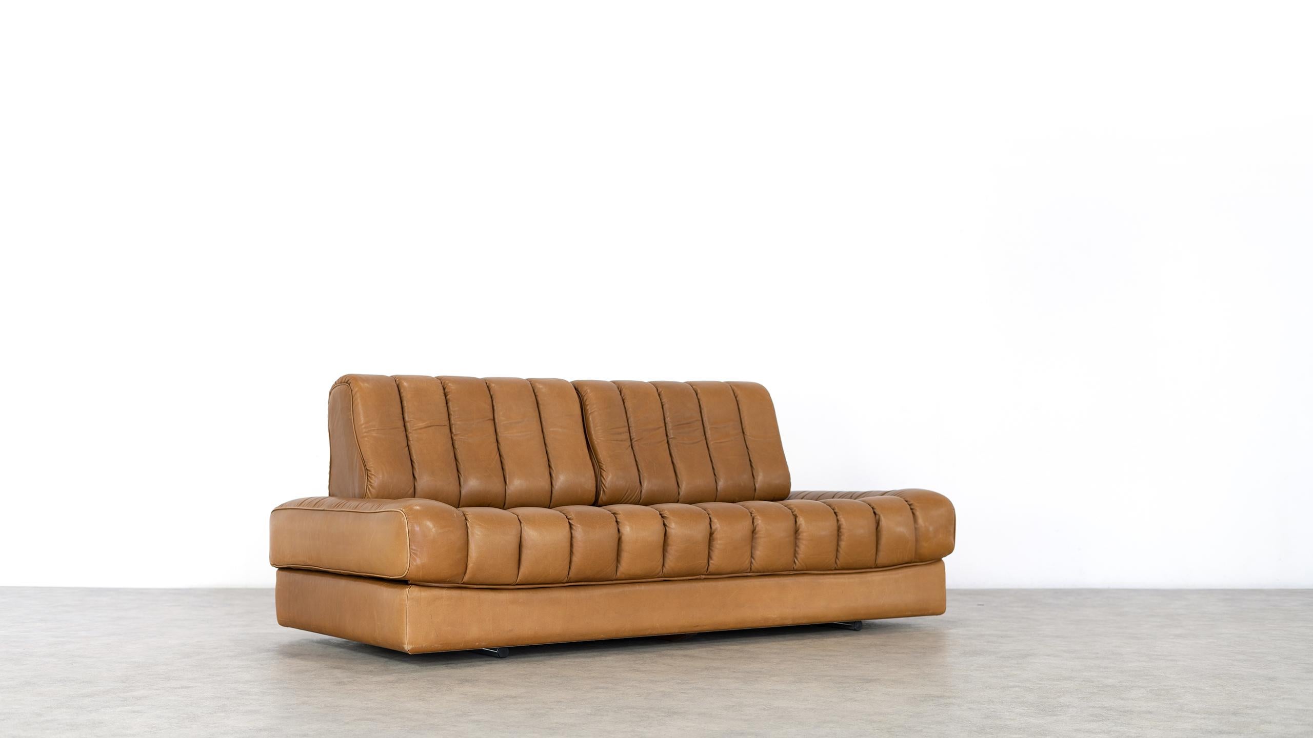 This daybed DS 85 in cognac leather was made in the 1970s by De Sede in Switzerland.

The versatile sofa and daybed can also be folded out into a double bed, the seat cover is invisibly connected by zipper.
The backrests are removable - the small