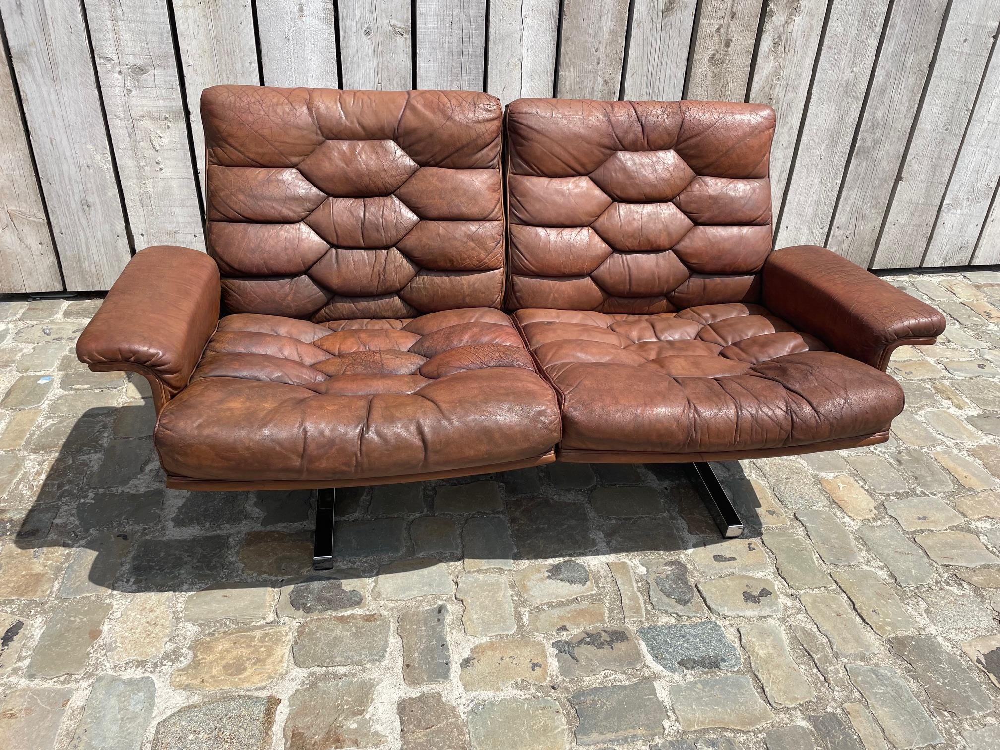 Sillón de 2 plazas De Sede DS35 de Robert Haussman en cuero marrón, un sofá de diseño icónico con una increíble pátina marrón, coñac, sin desgarros en el cuero pero bien desgastado como debe ser.
El cuero era originalmente negro, aún visible en las