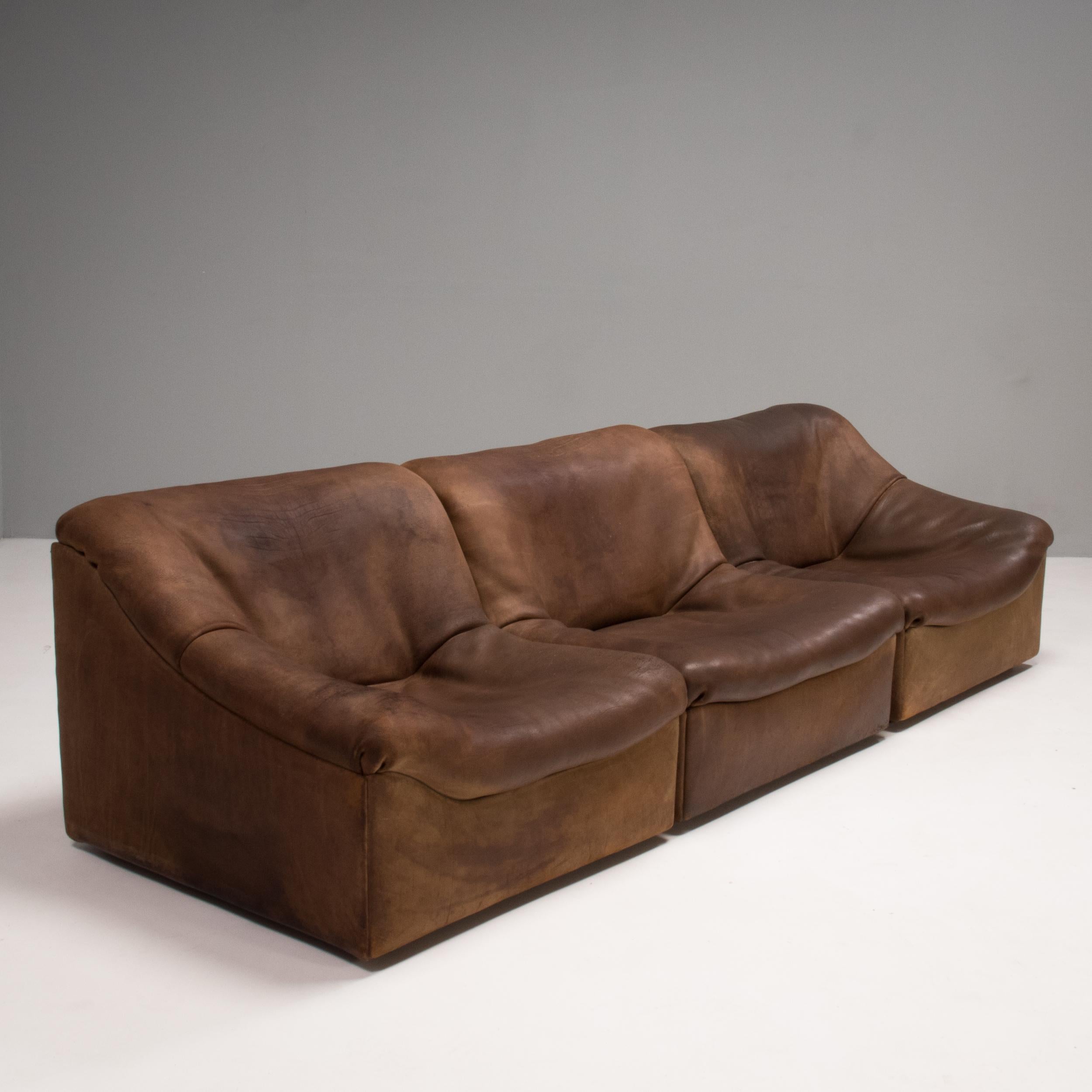 An iconic 1970s design, the DS46 chairs by De Sede are perfect for creating a sectional sofa or used as separate lounge chairs for a multitude of seating options.

Upholstered in soft brown leather, the set consists of two armchairs and one single