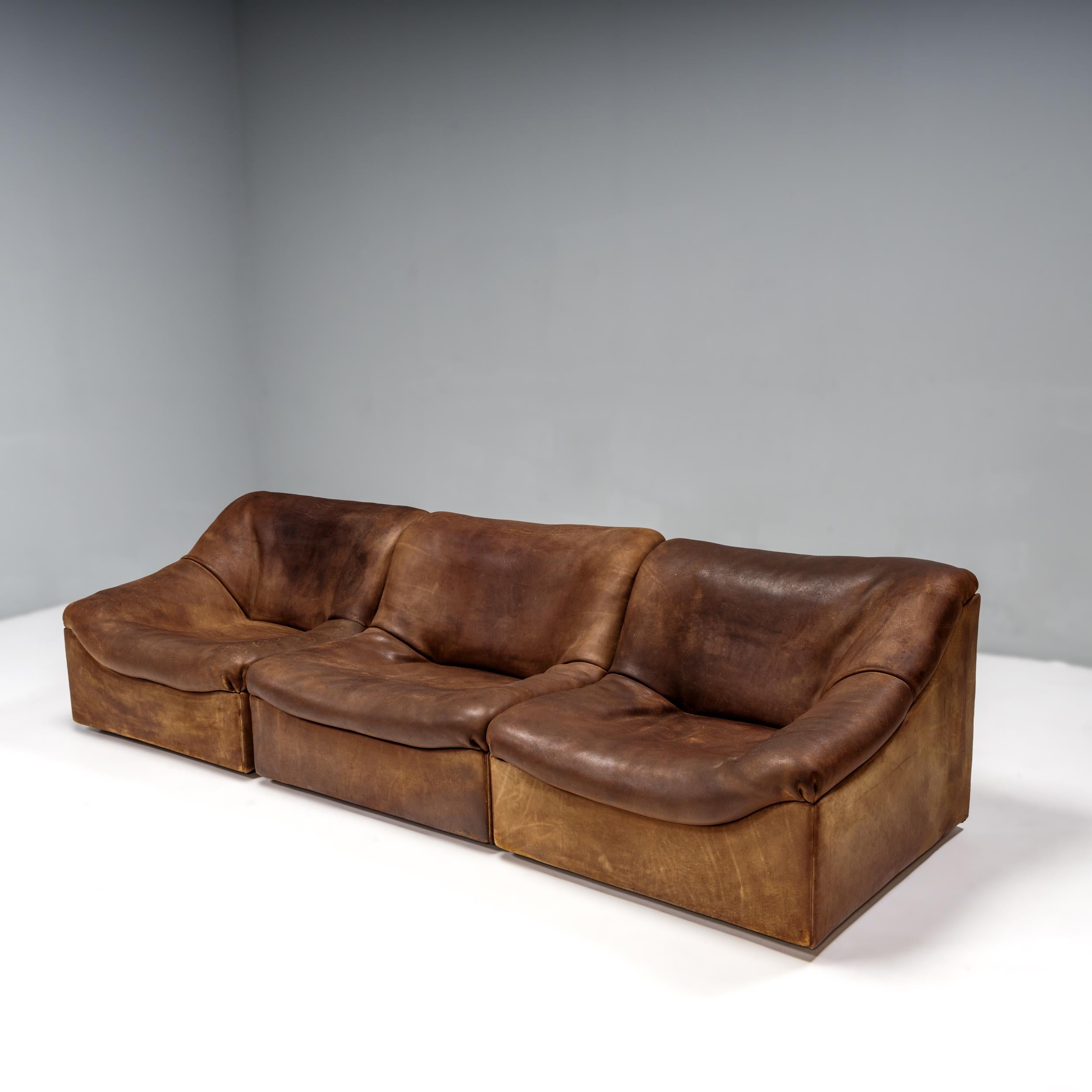 An iconic 1970s design, the DS46 chairs by De Sede are perfect for creating a sectional sofa or used as separate lounge chairs for a multitude of seating options.

Upholstered in soft brown leather, the set consists of two armchairs and one single