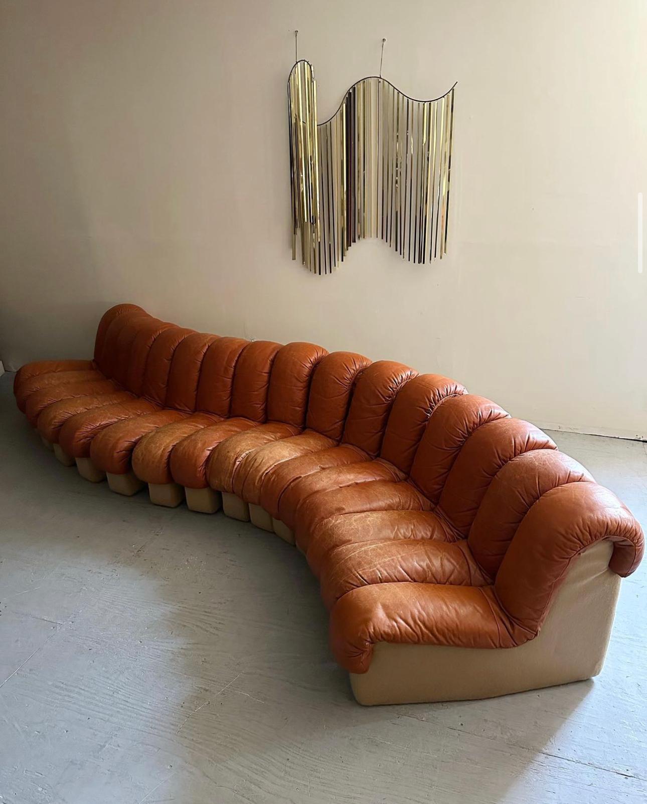 A monumental midcentury Classic designed in collaboration by Ueli Bergere, Elenora Peduzzi-Riva, Heinz Ulrich and Klaus Vogt at De Sede, Switzerland. Comes wrapped in a cognac colored leather upholstery. This modular sectional sofa with endless