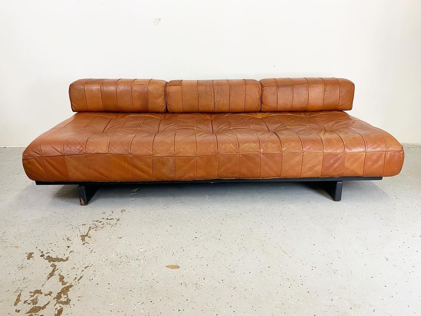 An excellent vintage example of the Patchwork Daybed in good condition. Low seat with removable arm. This piece is deep for lounging and has room to relax and lay. Leather shows age appropriate wear and the painted birch frame has some paint loss.
