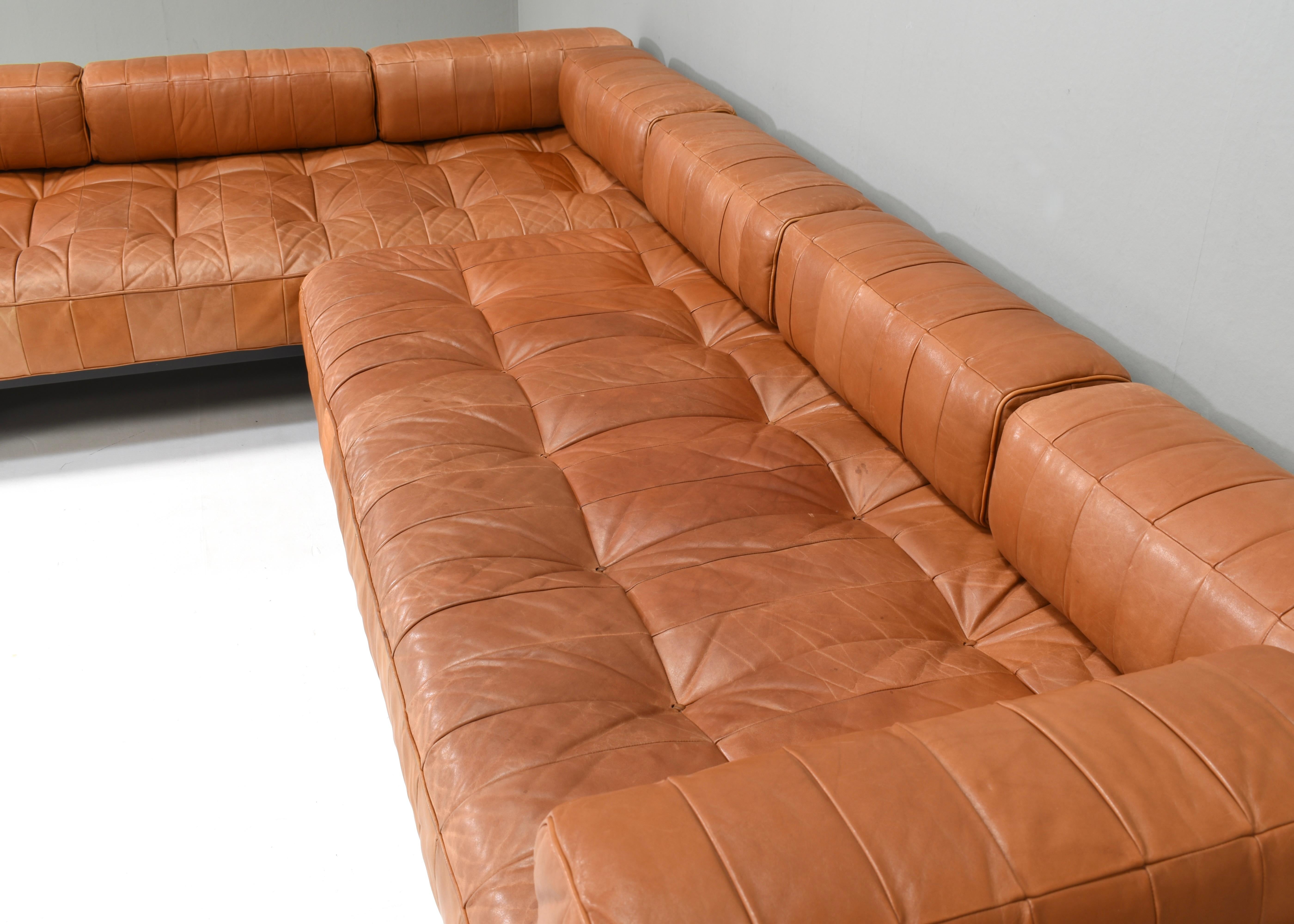 Wir stellen Ihnen dieses wunderschöne, cognacbraune DS80-Patchwork-Sofa von De Sede vor. Die Arm- und Rückenstützen aus lackiertem Holz können für verschiedene Aufstellungen im Gebrauch nach links und rechts sowie nach hinten und vorne verschoben