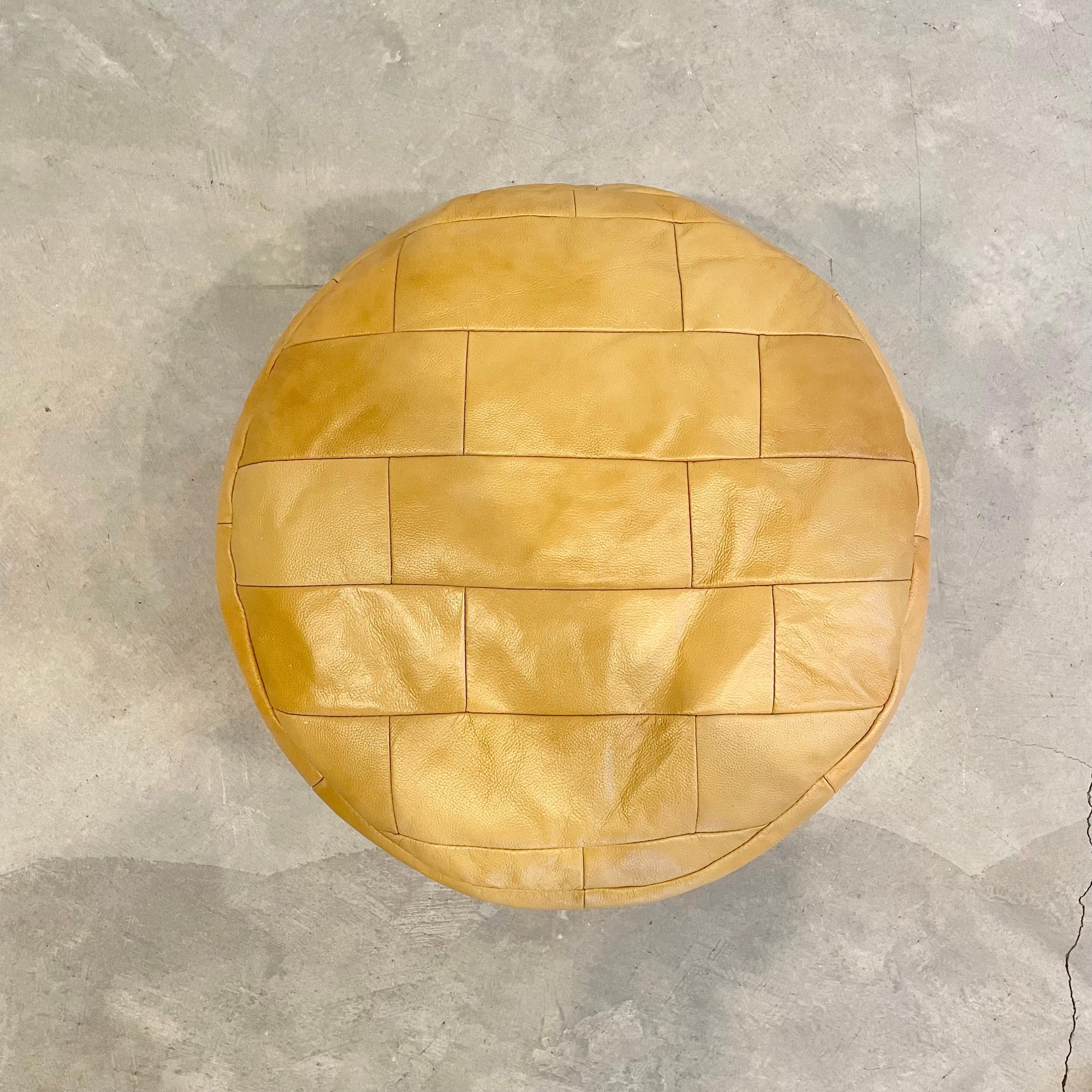Stunning golden brown leather pouf/ottoman by Swiss designer De Sede with square patchwork. Handmade with wonderful faded patina. Gorgeous accent piece. Good vintage condition. Wear appropriate with age. Brand new filler. Perfect living room decor,