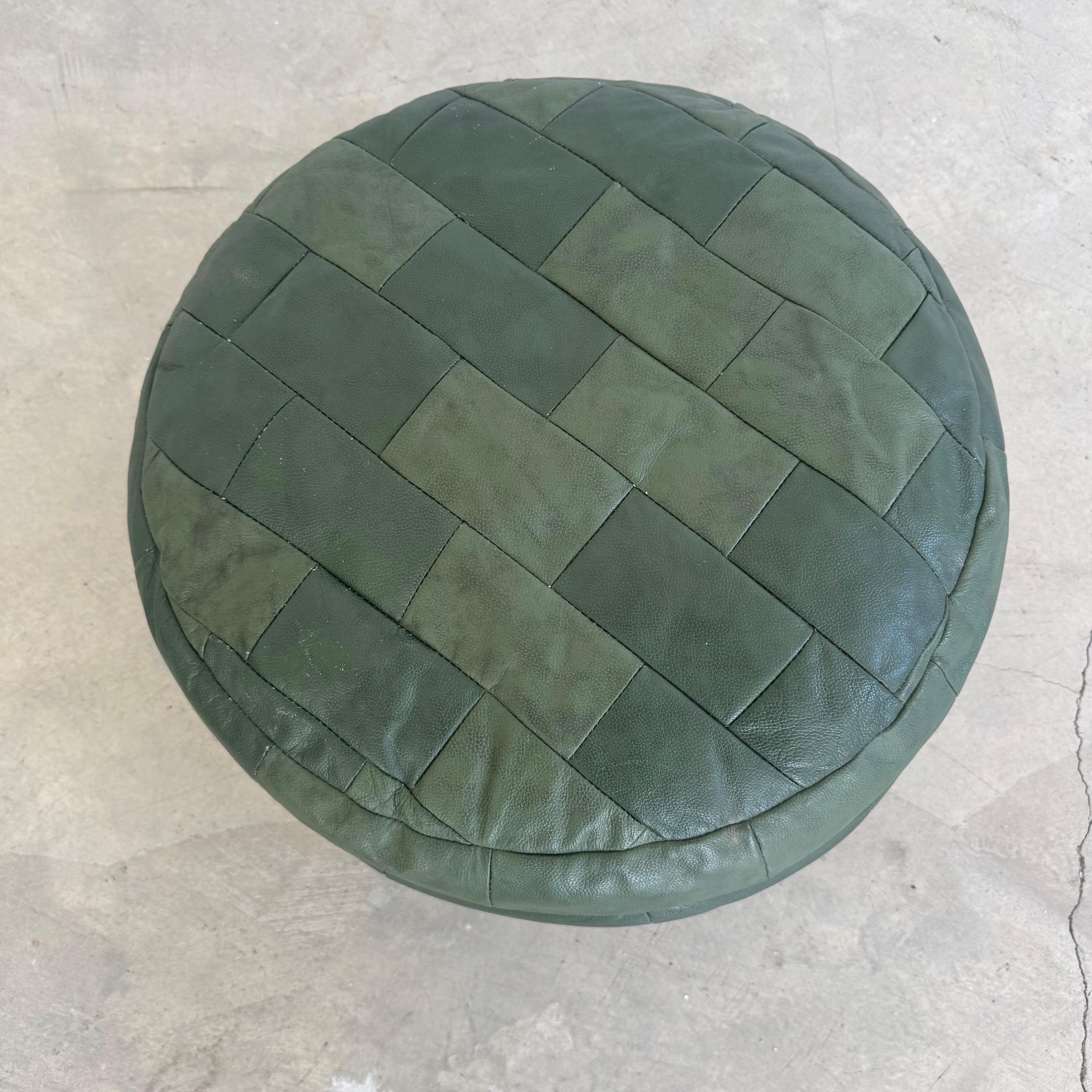 Hübscher Lederhocker von De Sede, der in den 1970er Jahren in der Schweiz hergestellt wurde. Dieses mit dem charakteristischen Patchwork-Leder gepolsterte Stück weist verschiedene Grüntöne auf, die in rechteckigen Lederflicken angeordnet sind. Das