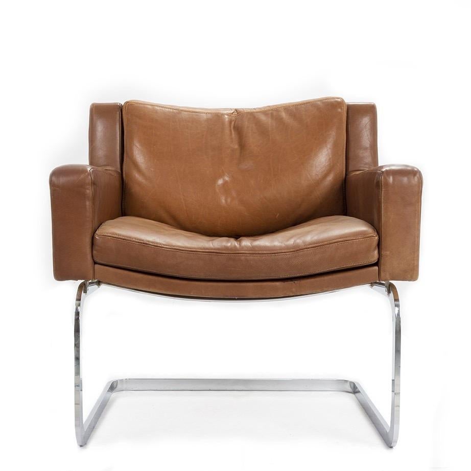 A vintage stylish armchair / lounge chair, Model #201 , upholstered in Cognac saddle leather with chrome cantilevered base, designed by Robert Haussmann for de Sede. Made in France.

Originally designed in 1957; this chair dates circa