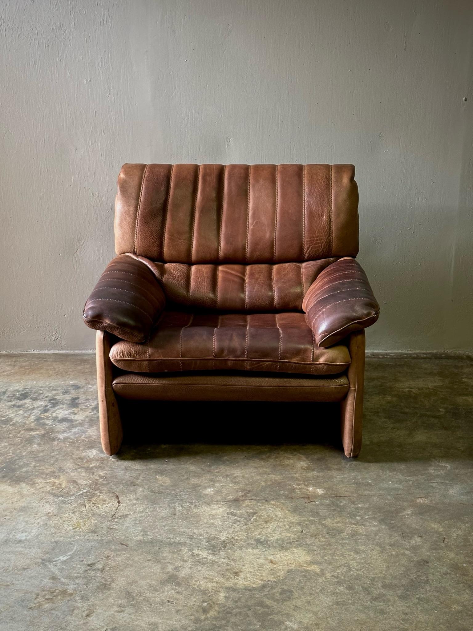 1970s chestnut leather armchair with vertical striation detailing, by iconic Swiss leather manufacturer De Sede. Comfortable and capacious with a sleek midcentury silhouette. 

Switzerland, circa 1970

Dimensions: 35.4W x 35.4D x 30H