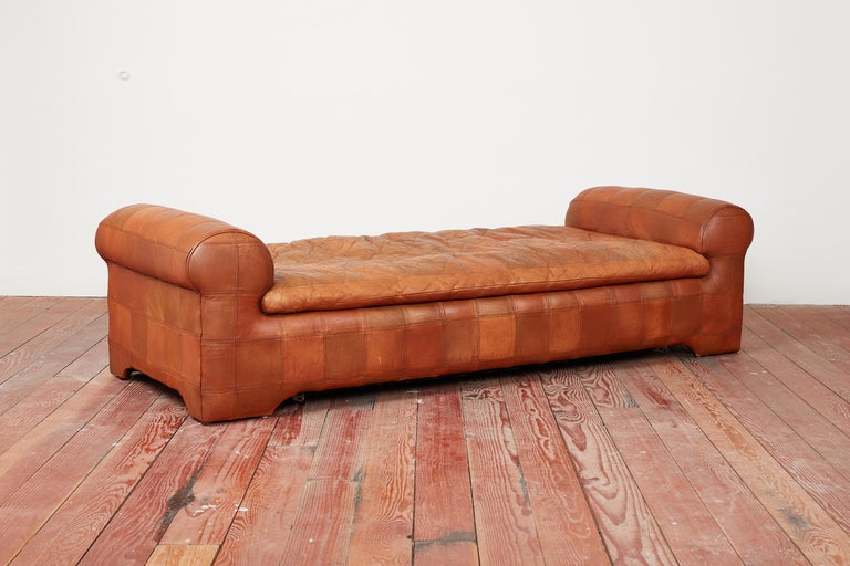 Unique leather daybed by De Sede circa 1970's.
Patchwork caramel leather with bench seat and 2 cylindrical headboard / footboard or armrests. 
Converts into pull out double bed under the seat cushion.
Wonderful patina to leather.
 