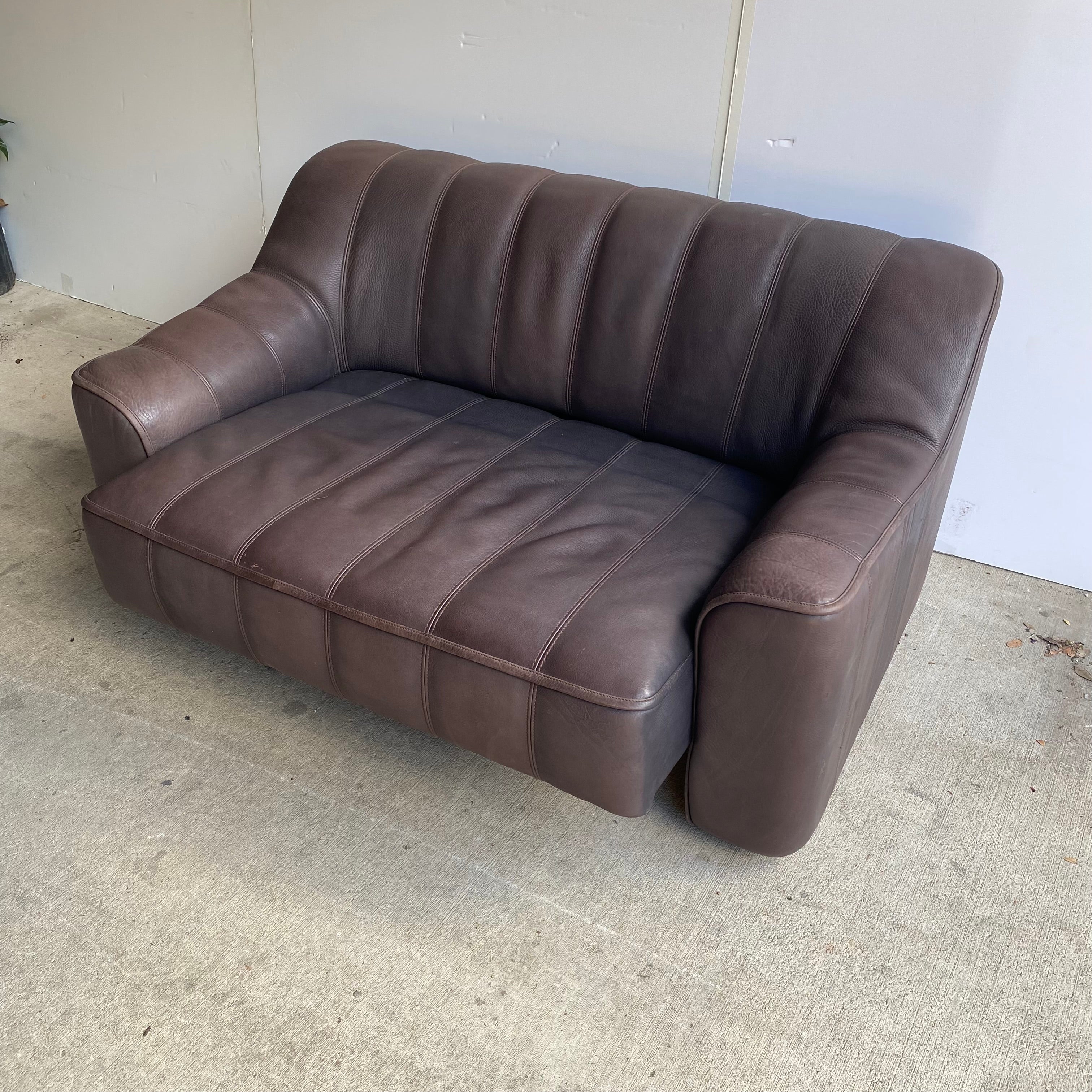 Mid-Century Modern two-seater DS-44 loveseat by Swiss maker, De Sede, in thick channelled bull hide. Seats extend with a gentle pull. Dark brown, comfortable and with leather in beautiful condition.