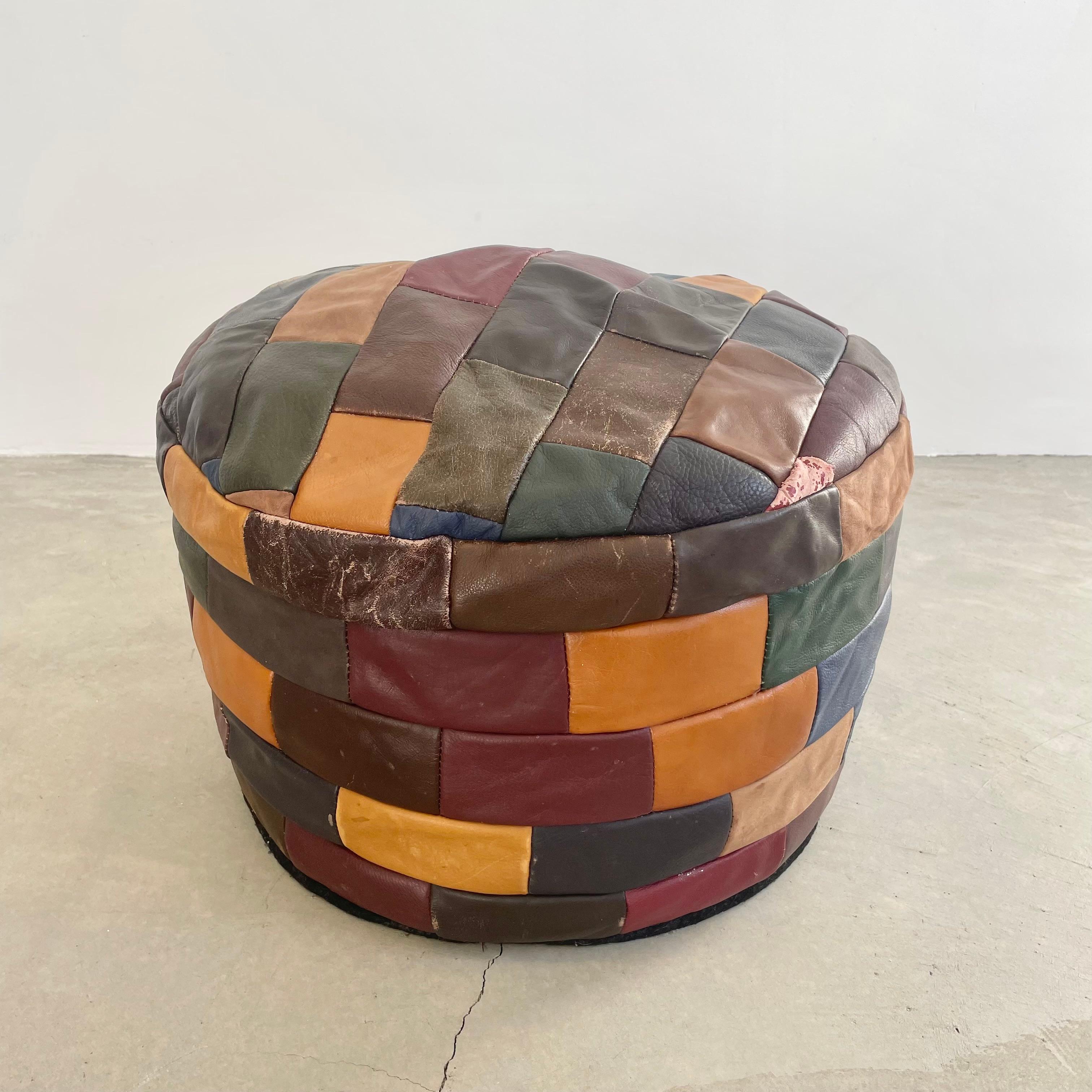 Gorgeous multicolored leather pouf/ottoman by Swiss designer De Sede with square patchwork. Handmade with wonderful faded patina of varying degrees of red, green, brown, tan, blue and purple. Design and colors are reminiscent of Northern African