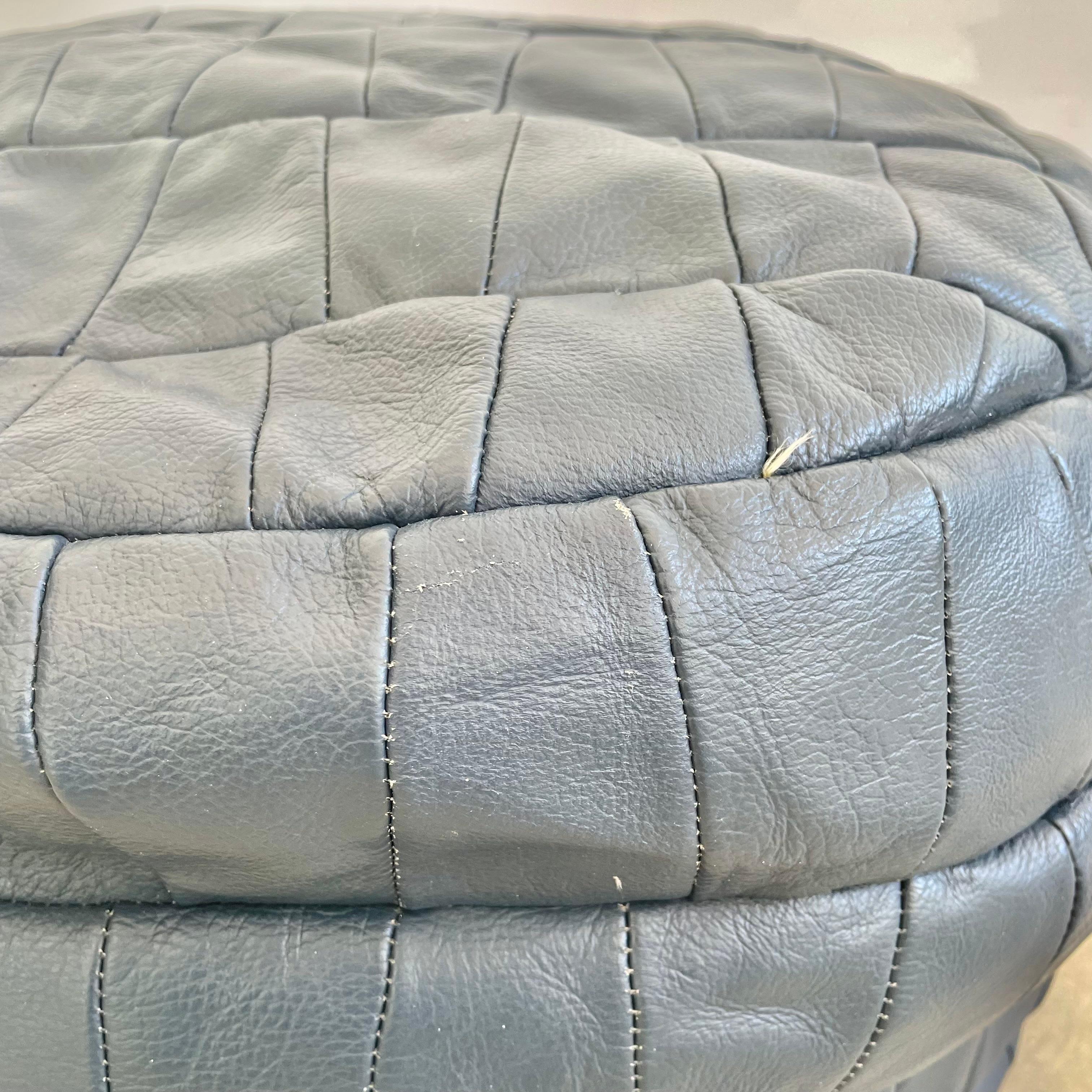 Stunning navy blue leather pouf/ottoman by Swiss designer De Sede with trapezoidal patchwork. Handmade with wonderful light patina. Gorgeous accent piece. Good vintage condition with soft supple leather. Brand new filler. Perfect living room decor,