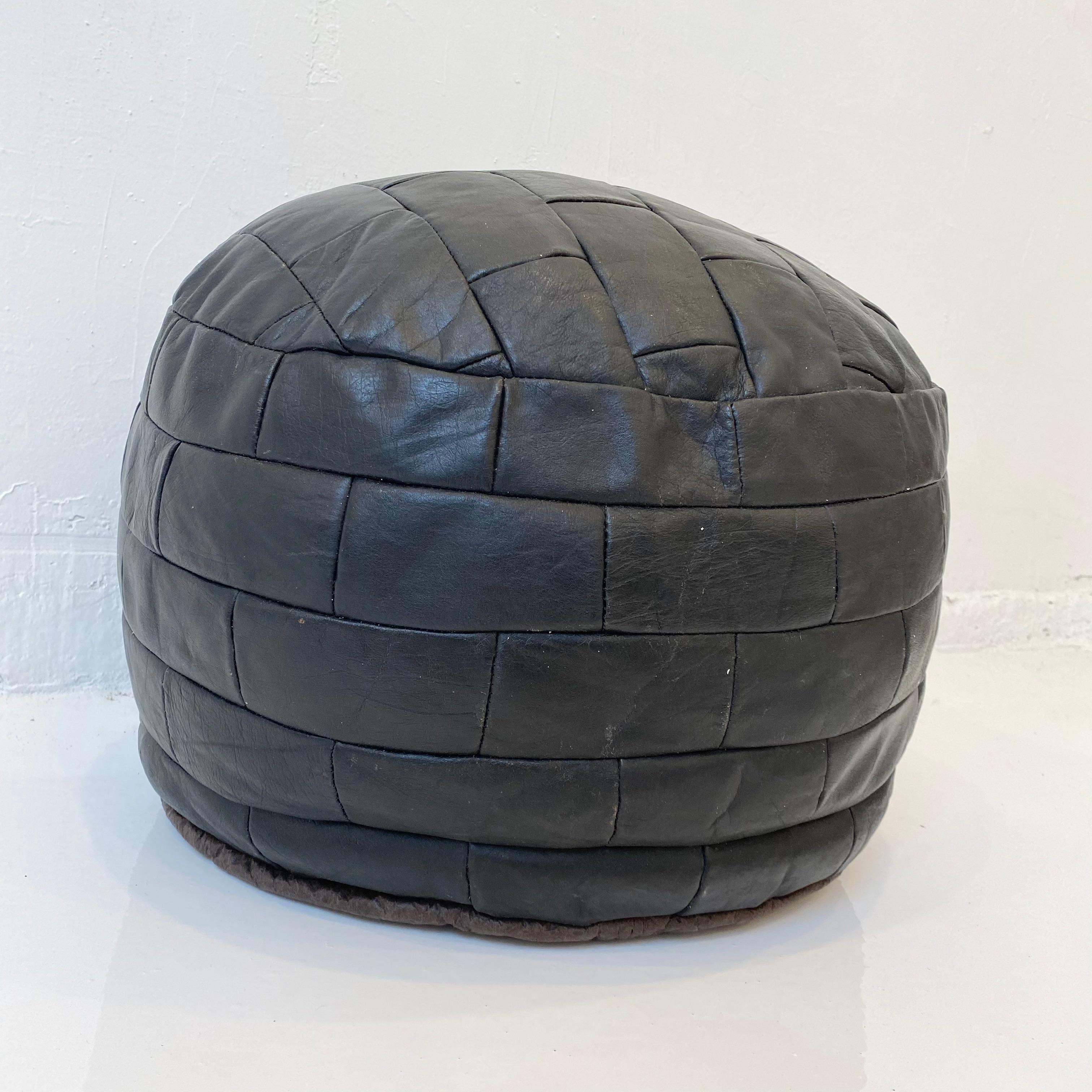 Gorgeous black leather pouf by Swiss designer De Sede with small rectangular patchwork. Perfect accent piece. Good vintage condition. 

 