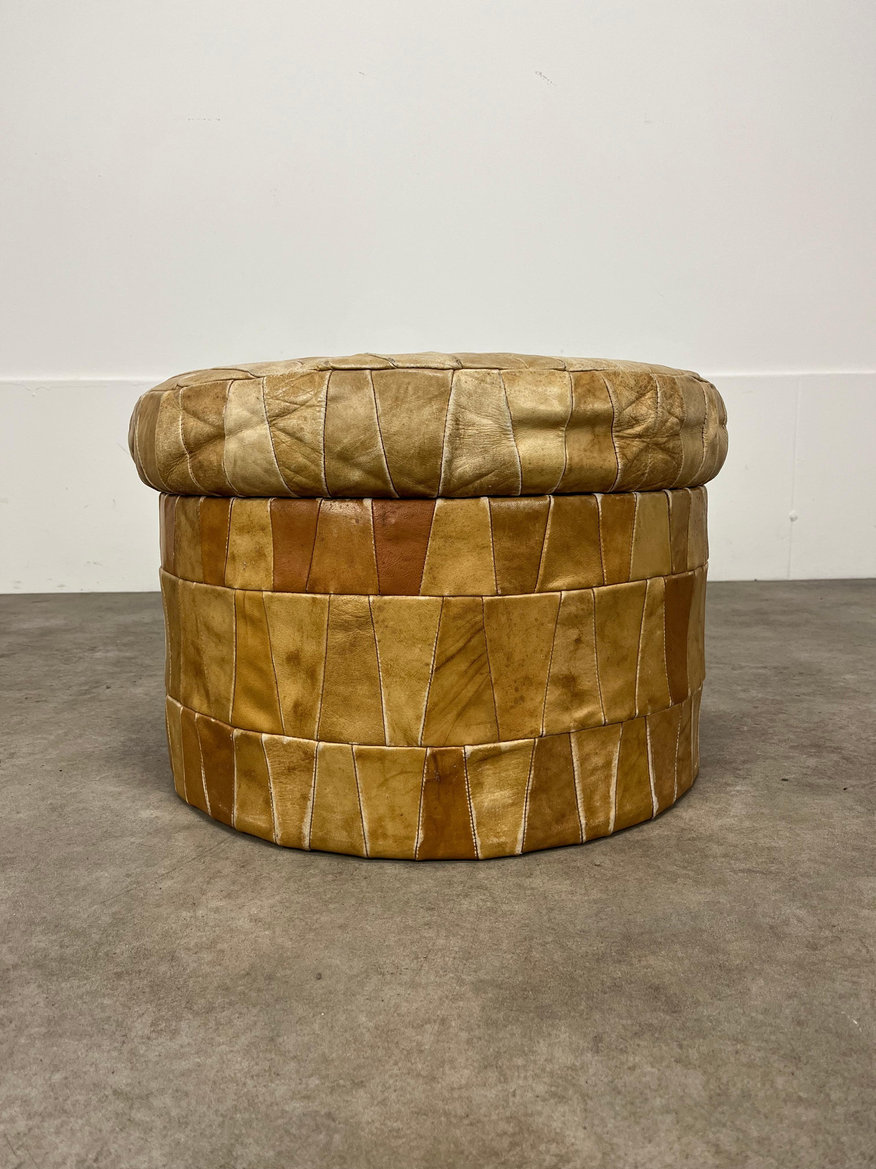 Pouf/ottomana rotondo vintage di De Sede con contenitore (profondità del contenitore 22 cm), realizzato in pelle chiara patchwork. 

Buone condizioni, bella patina di pelle. 