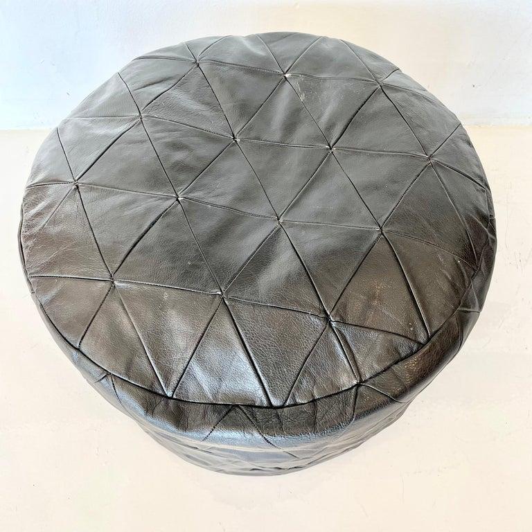 Gorgeous black leather pouf by Swiss designer De Sede. Triangular patchwork design. Good vintage condition. Perfect accent piece.