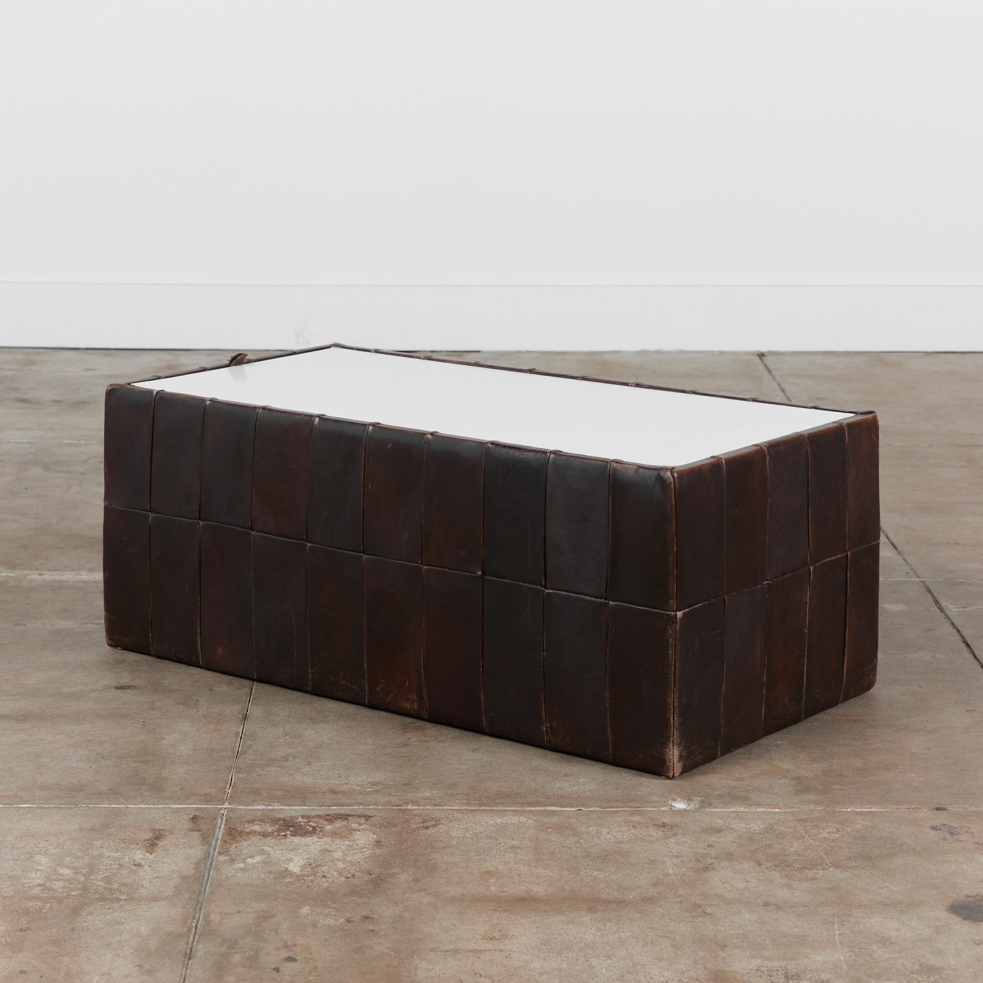 Leather patchwork storage cube by De Sede, Switzerland, circa 1960s. The cube features a patinated patchwork leather exterior around the entire cube with a removable white laminate top. The top of the table can open for storage or simply be used as