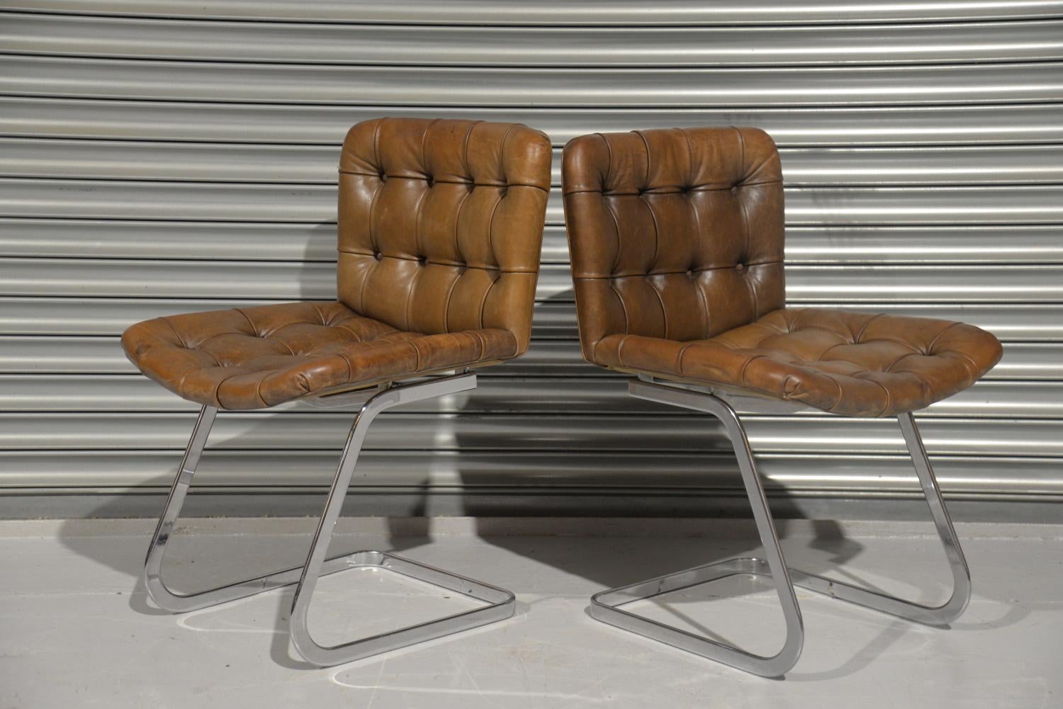 We are delighted to bring to you this set of two RH-304 chairs designed by Robert Haussmann and manufactured in Switzerland by de Sede during the 1960s. The set is upholstered in brown leather with buttons. The frames are made of chrome-plated