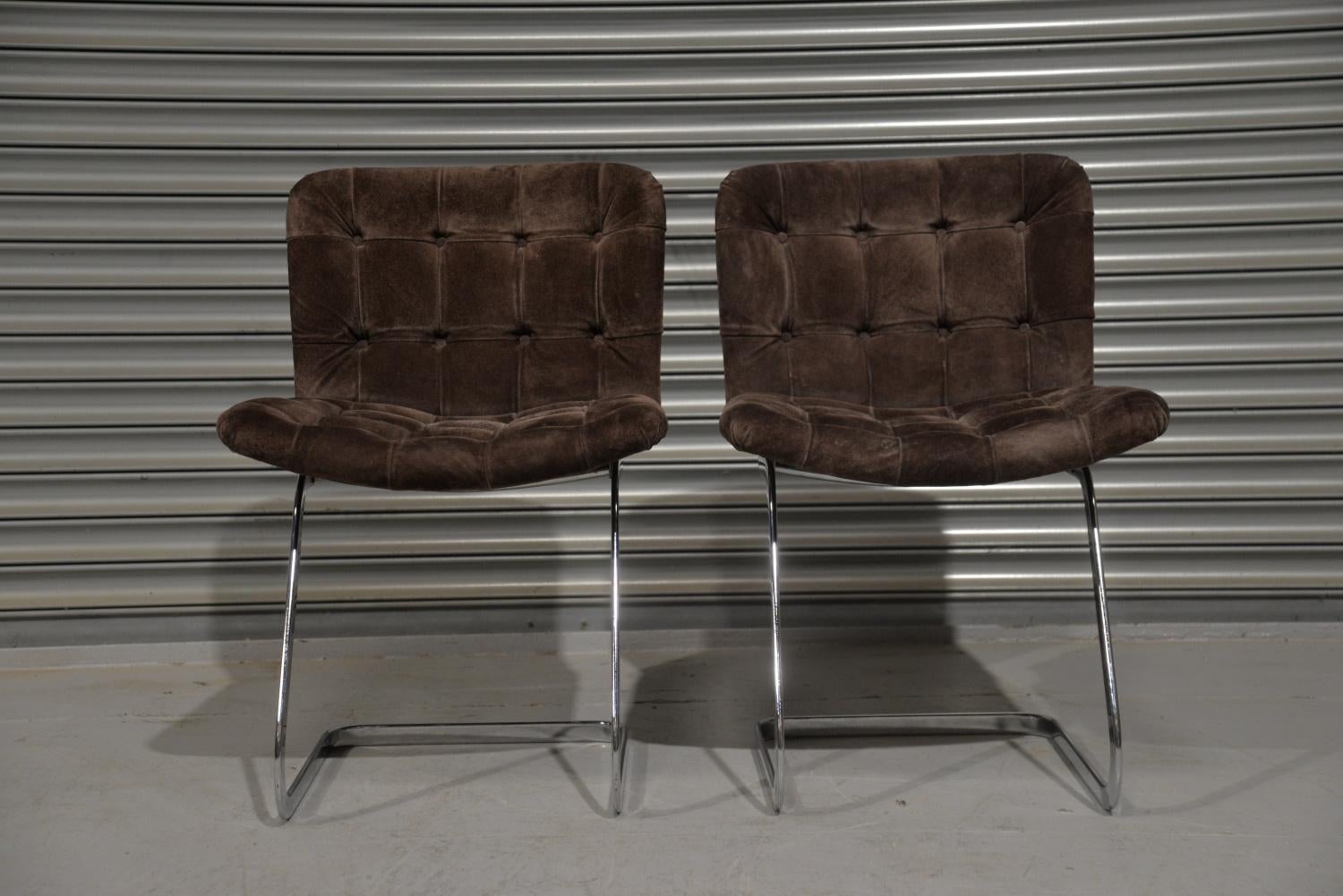 We are delighted to bring to you this set of two RH-304 chairs designed by Robert Haussmann and manufactured in Switzerland by de Sede during the 1960s. The set is upholstered in brown leather with a velvet texture and buttons. The frames are made
