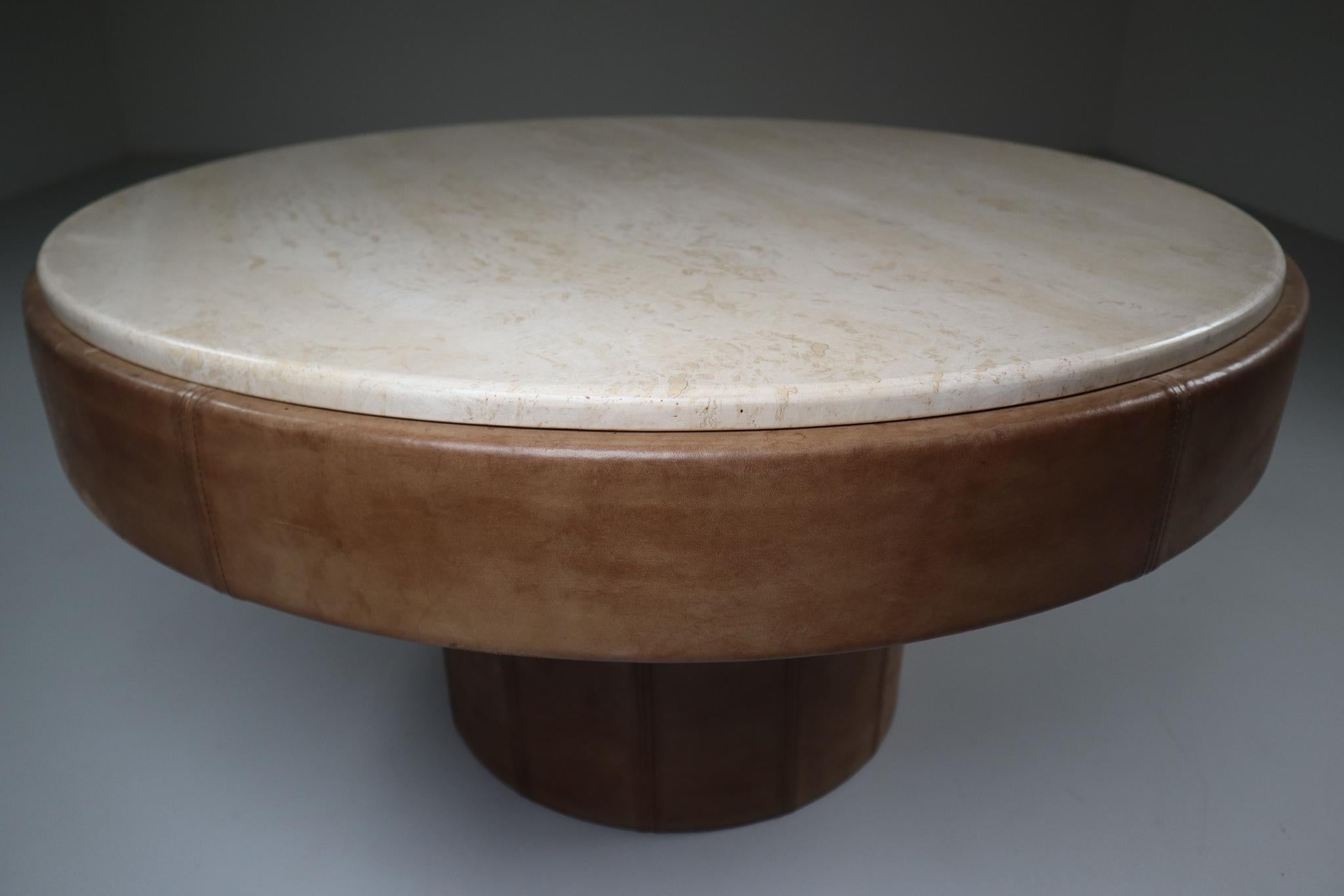 De Sede round coffee table 1970s, made of the highest quality buffalo leather in a unique patinated cognac color leather and soft colored marble top. Remains in excellent and original condition. The leather and construction are very good vintage