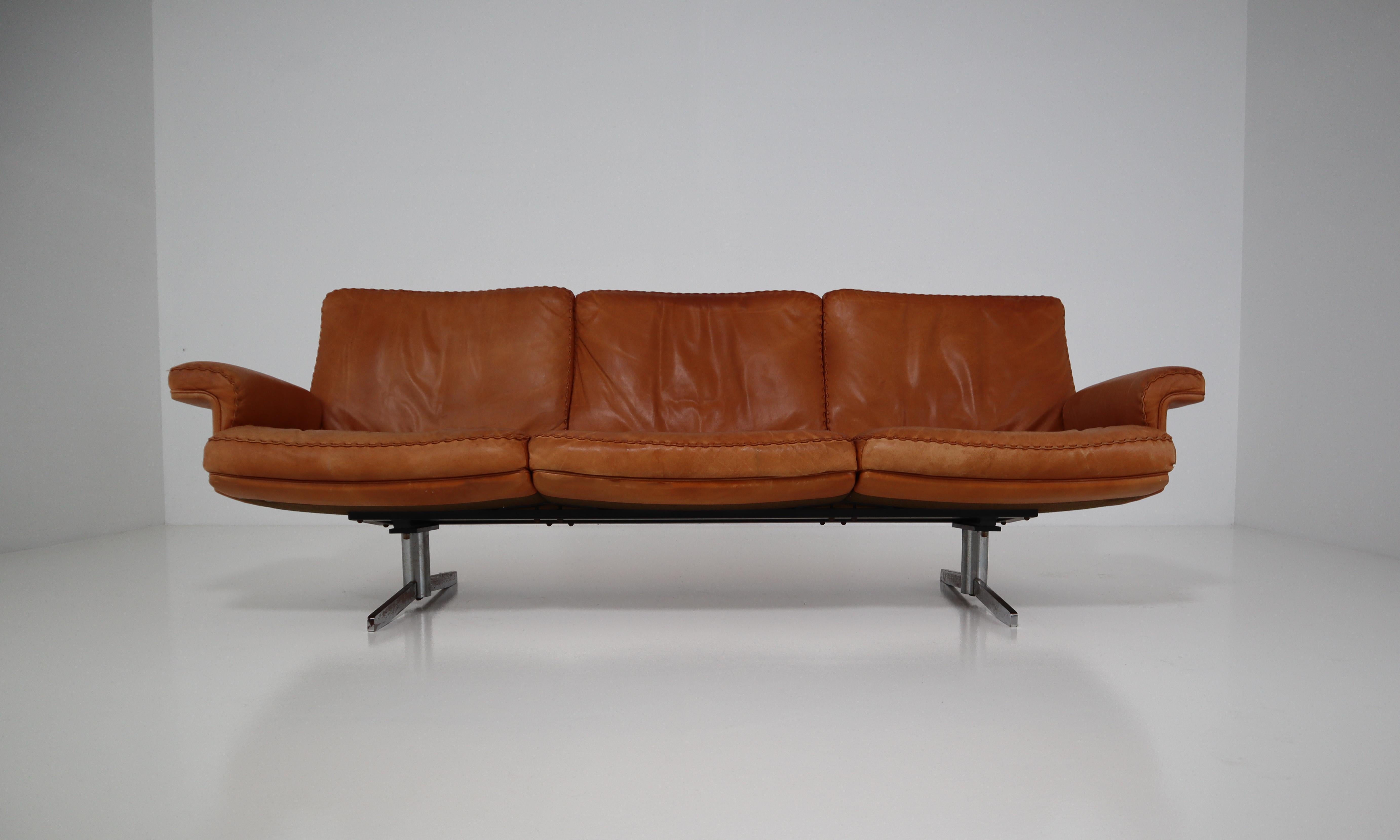 De Sede DS 35 three-seat sofa is upholstered in cognac aniline leather with a whipstitch edge detail. It was manufactured in the late 1960s by De Sede from Switzerland. This three seater sofa stands on polished chrome plated legs. This sofa is in an