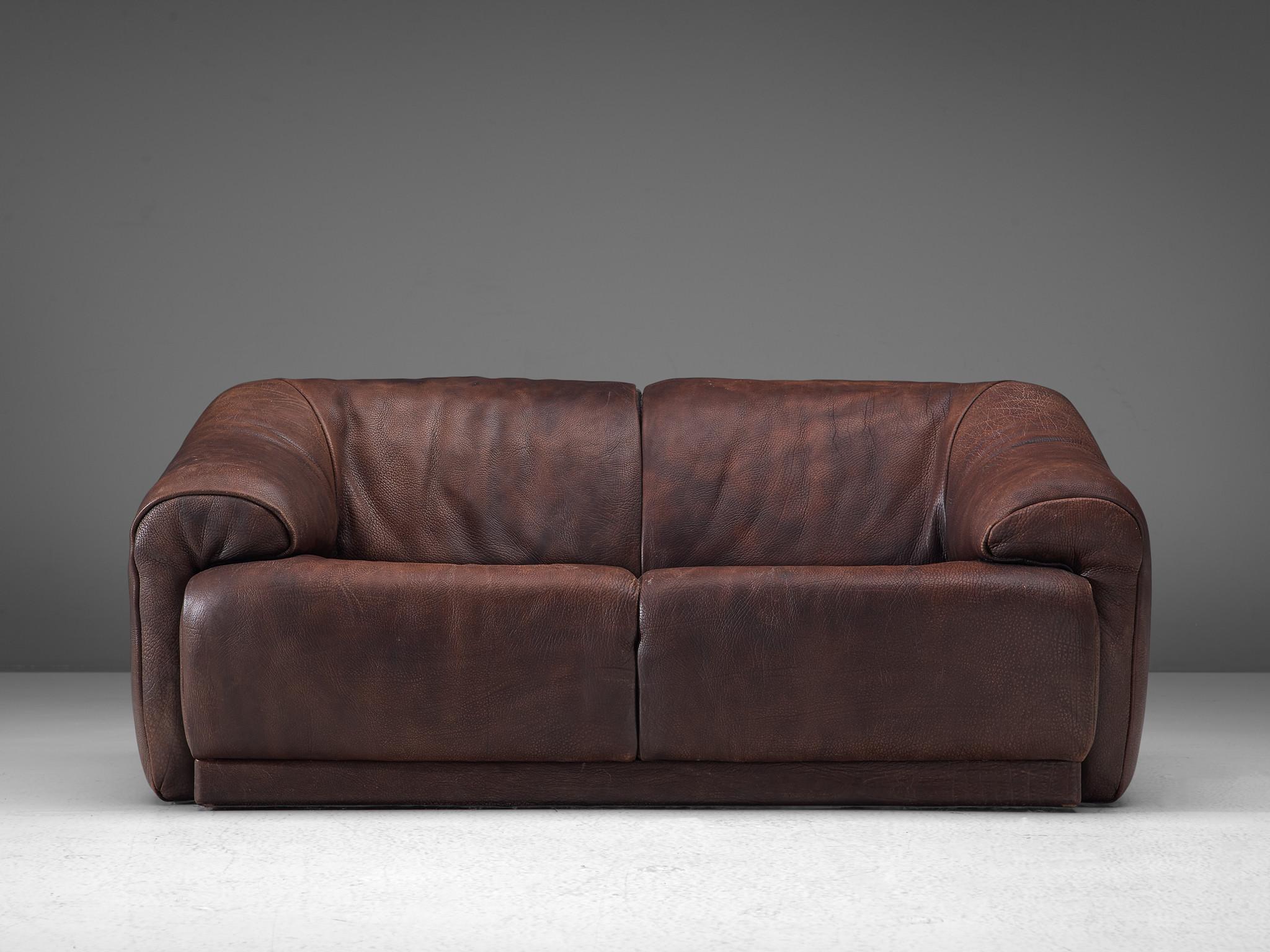 De Sede, sofa, leather, Switzerland, circa 1970.

This model is characterized by a voluminous, round seat whose armrests run diagonally from the backrest. This piece of furniture is designed to provide an ultimate level of comfort due to the thick