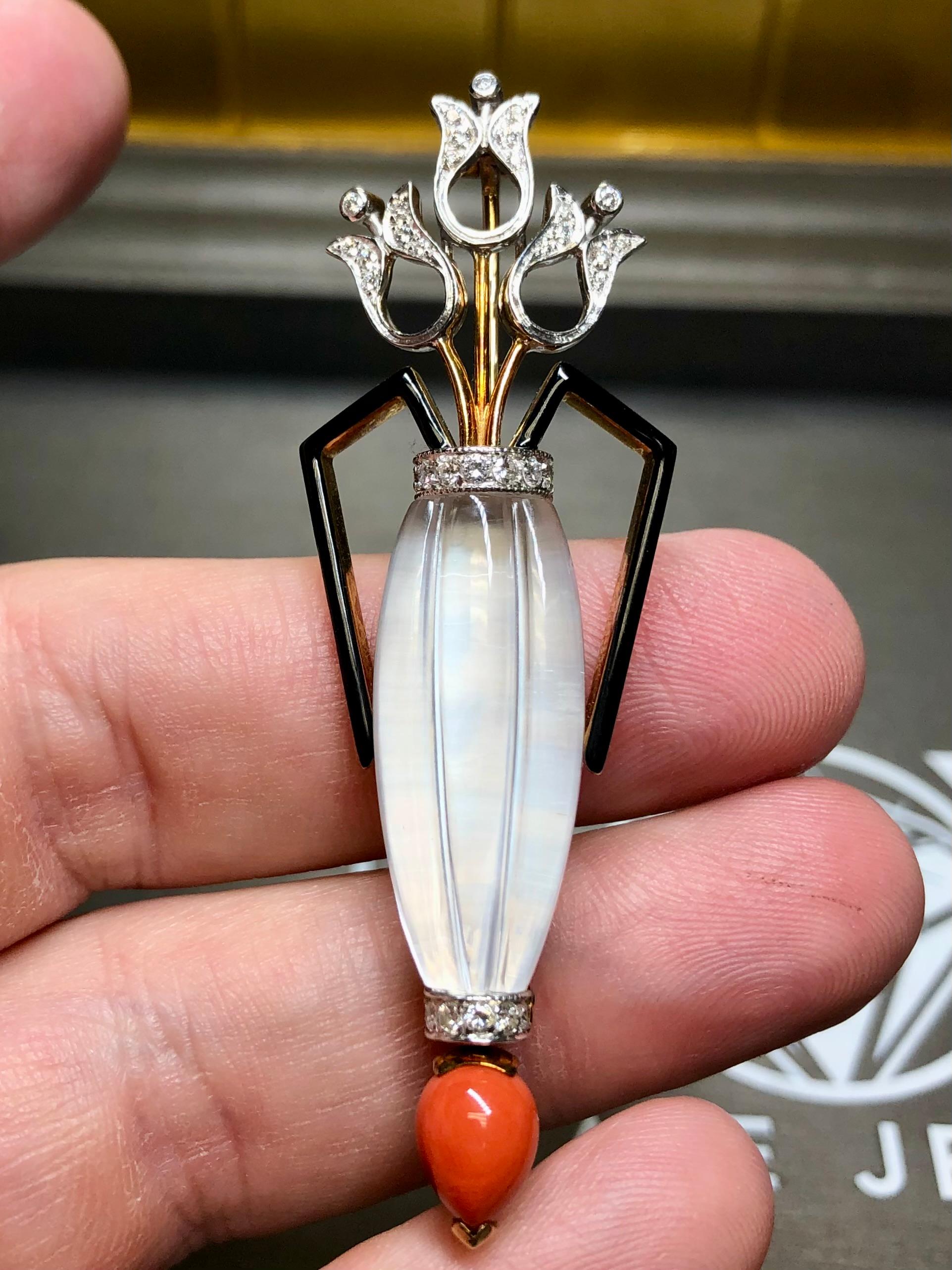 A lovely brooch by Italian maker De Vecchi. It has been masterfully crafted in 18K yellow and white gold and adorned with carved rock crystal, cabochon natural coral, black enamel and approximately .48cttw in G-H color Vs1-Si1 clarity round