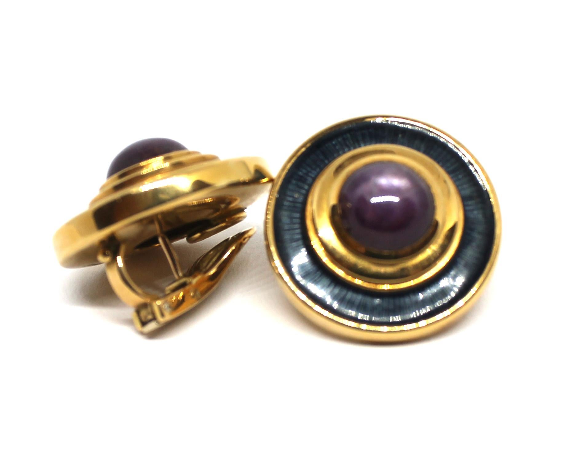 Oval ruby cabachon collet set within a blue guilloche enamel surround.  The ear clips ensuite mounted in 18 karat yellow gold, signed de Vroomen both with makers mark. London hallmarks. Earclip length 2.4cm.  Earclips dated 1991.