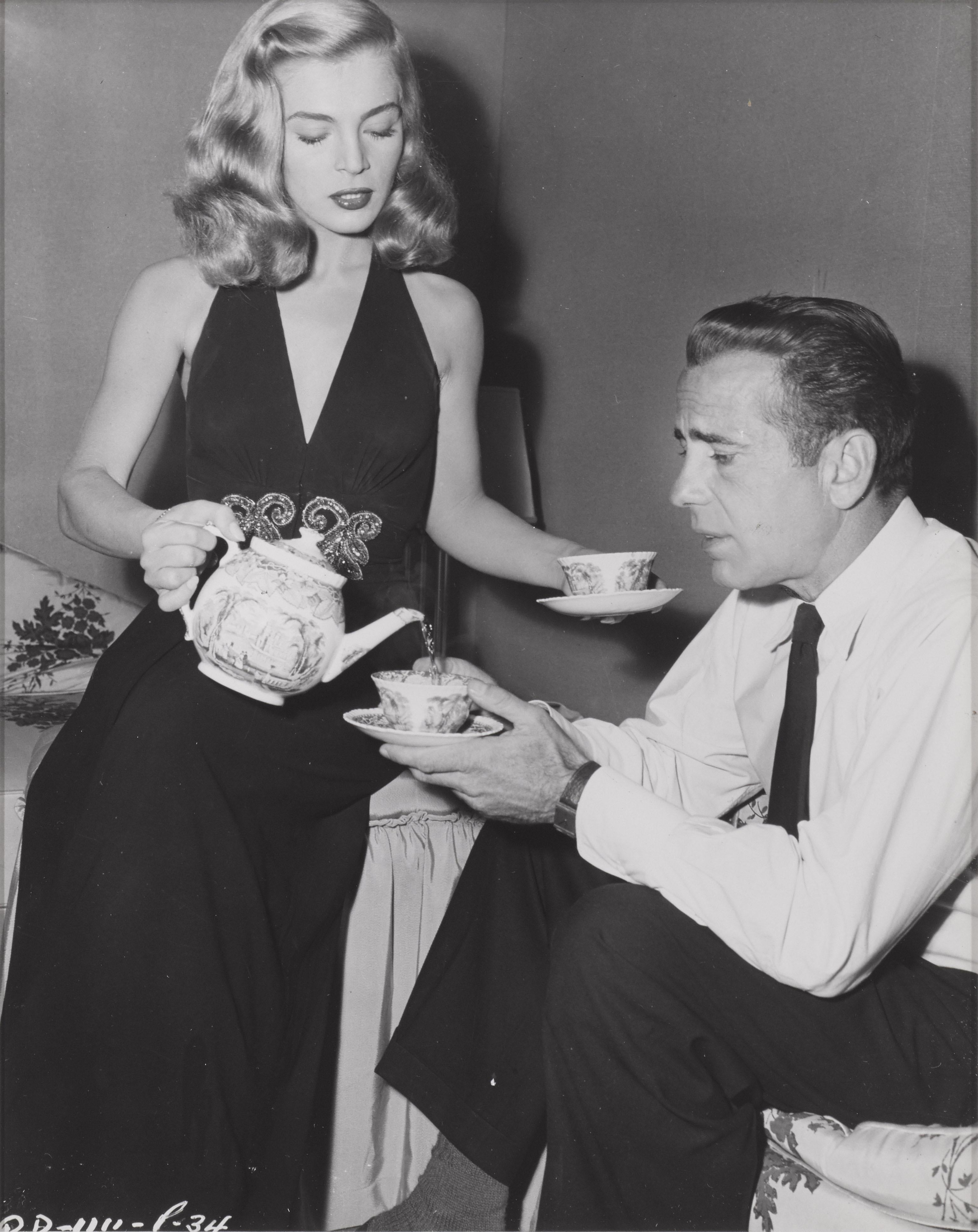 Original candid photographic production still for the 1947 Film Noir starring Humphrey Bogart and Lizabeth Scott.
This film was directed by John Cromwell. This candid photographic production shows Lizabeth Scott pouring Humphrey Bogart tea between