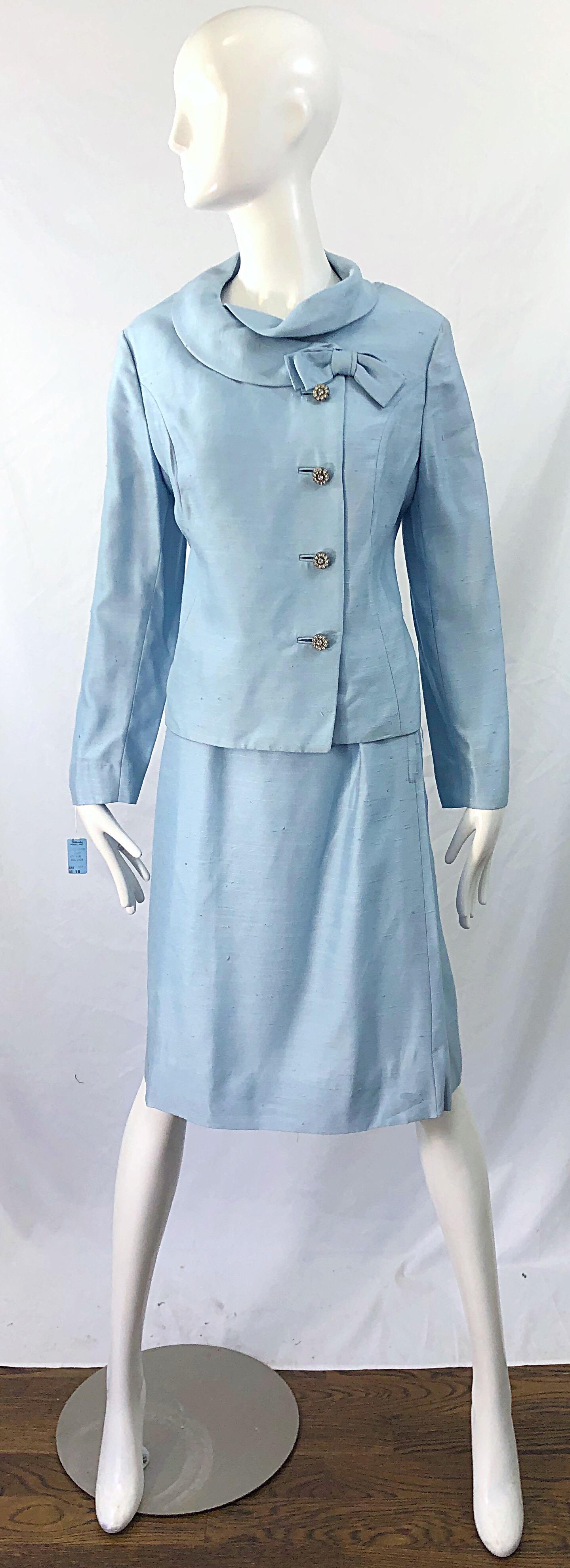Chic deadstock ( brand new with tags ) original 1960s Alvin Handmacher ( Weathervane Tailored by Handmacher ) baby blue skirt suit ! Features a tailored jacket with pre--tied bow at left collar. Rhinestone encrusted buttons up the front. High