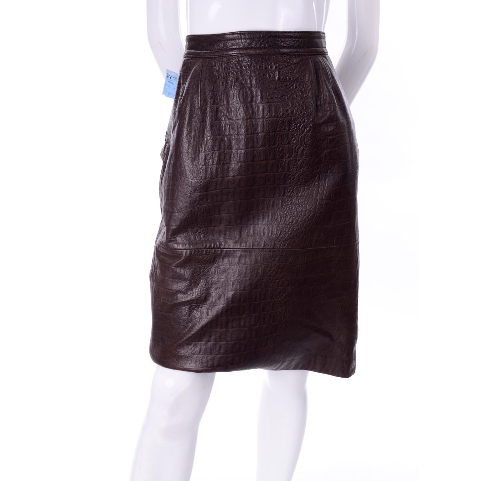 This is a gorgeous brown leather pencil skirt by Valentino with an alligator print embossing. It buttons and zips in the back, with two side flap pockets that button closed with two large buttons. It has a small kick flap in back and is fully lined
