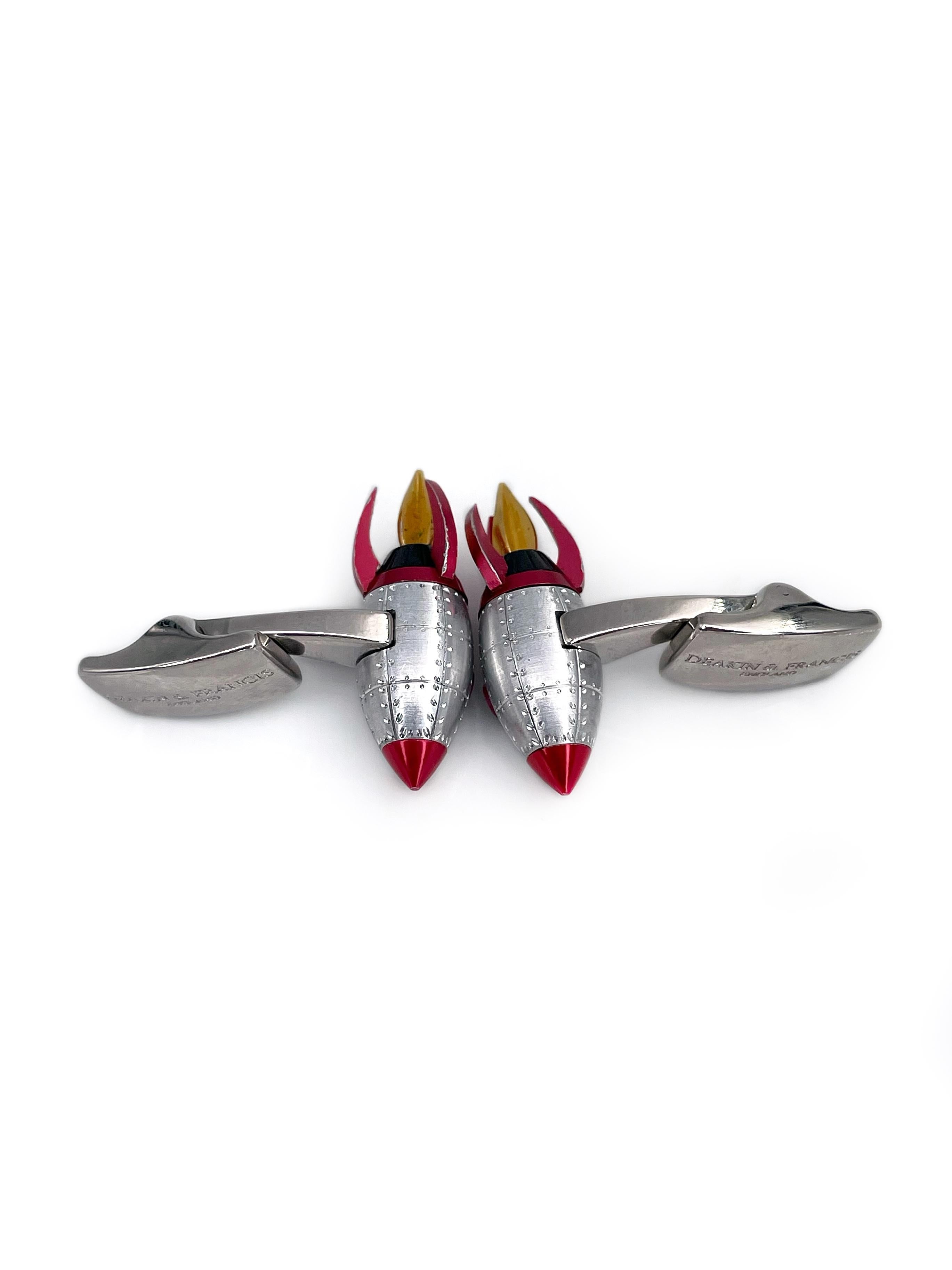 This is a playful pair of rocket cufflinks designed by Deakin & Francis in 2010’s. The piece is crafted in shiny base metal. It features red and yellow enamel details. By pulling down the lever on the back the flame shoots out of the bottom. It is a