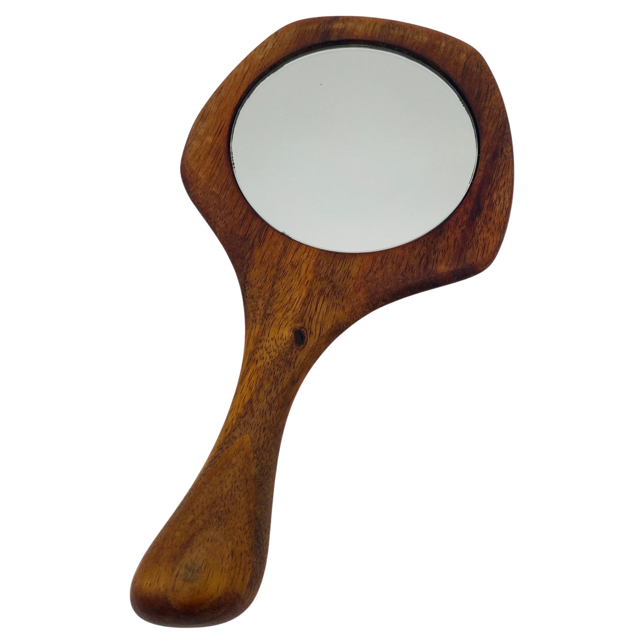 Il s'agit d'un rare miroir en bois de noyer fabriqué à la main par le designer californien Dean Santner. Vers 1970. Il est très agréable à tenir dans la main grâce à son bois sculpté et lisse. 