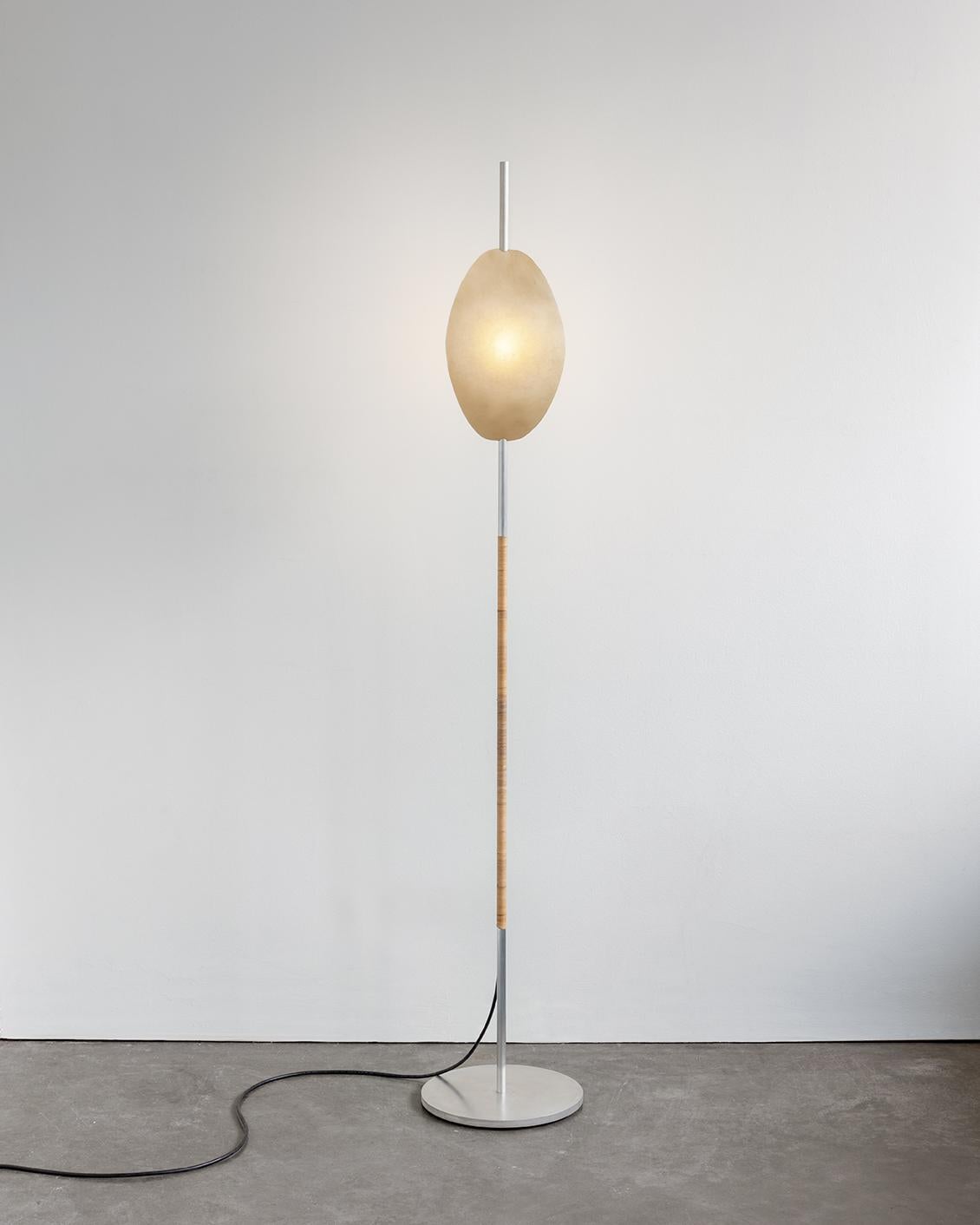 Deas light by Calen Knauf
Dimensions: D 28 x W 28 x H 161 cm
Materials: Aluminum, rattan, rawhide, resin

The Deas is an accent floor light consisting of a solid, waxed aluminum main support and base, hand wrapped in rattan. The diffuser