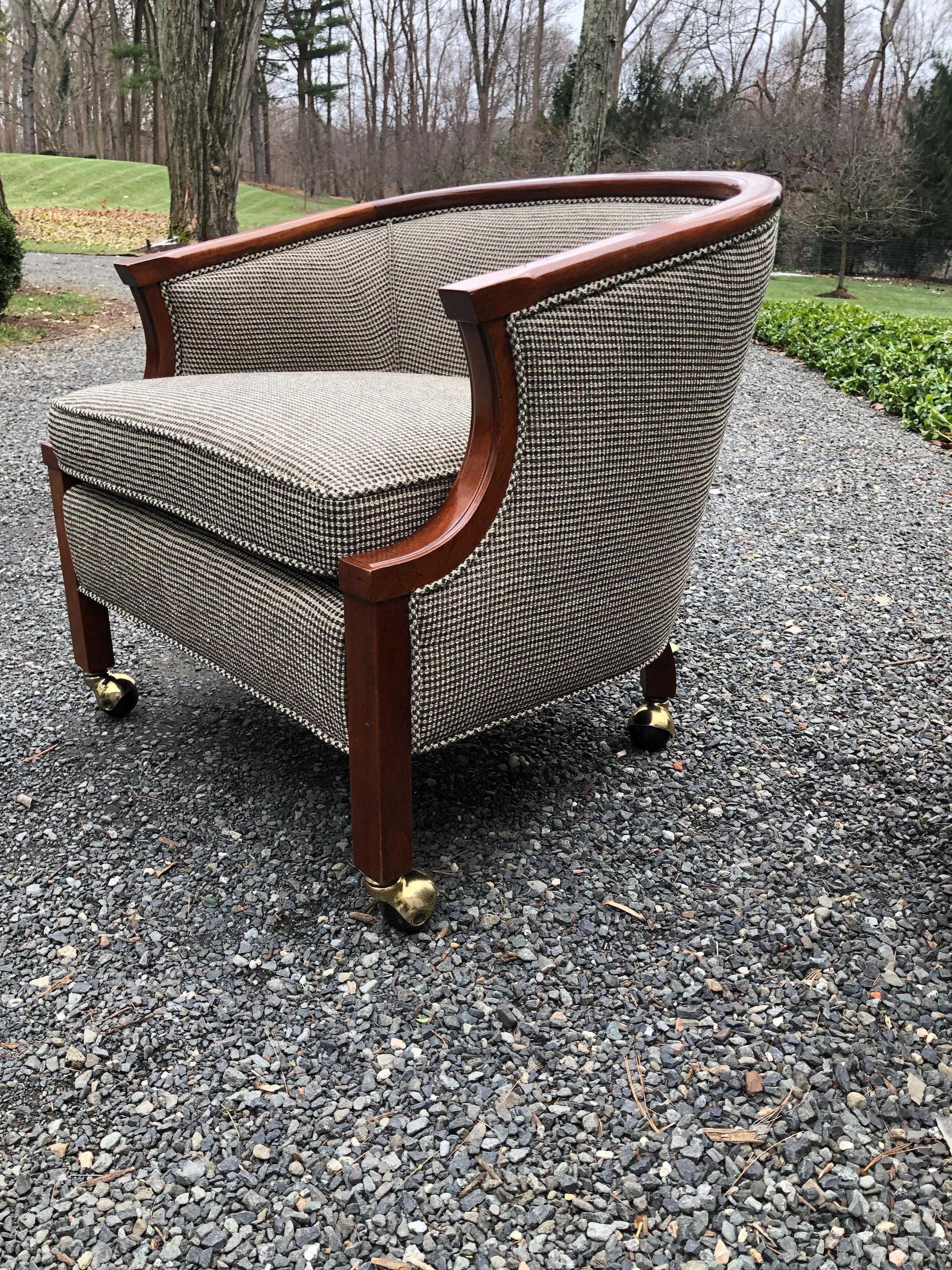 Great pair of midcentury club chairs by John Stuart newly upholstered in a black, taupe and ivory glen plaid wool blend fabric. The mahogany frames have been professionally polished and casters are original. Seat height is 17” seat interior width