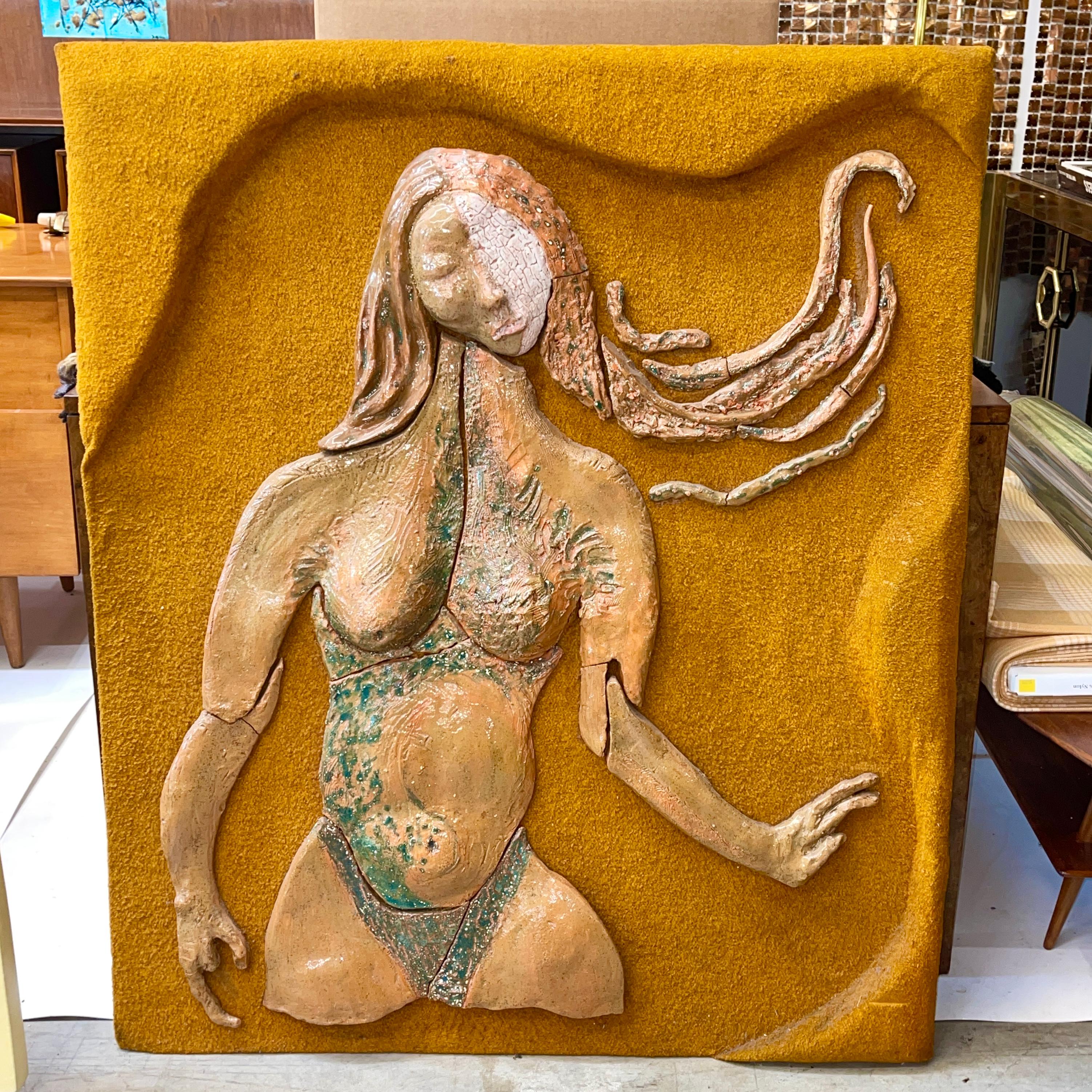 A modernist portrait of a semi-nude woman executed in segments of glazed ceramic mounted to a sculpted plywood panel clad in a coarsely woven textile in honey mustard color.
Signed en verso 