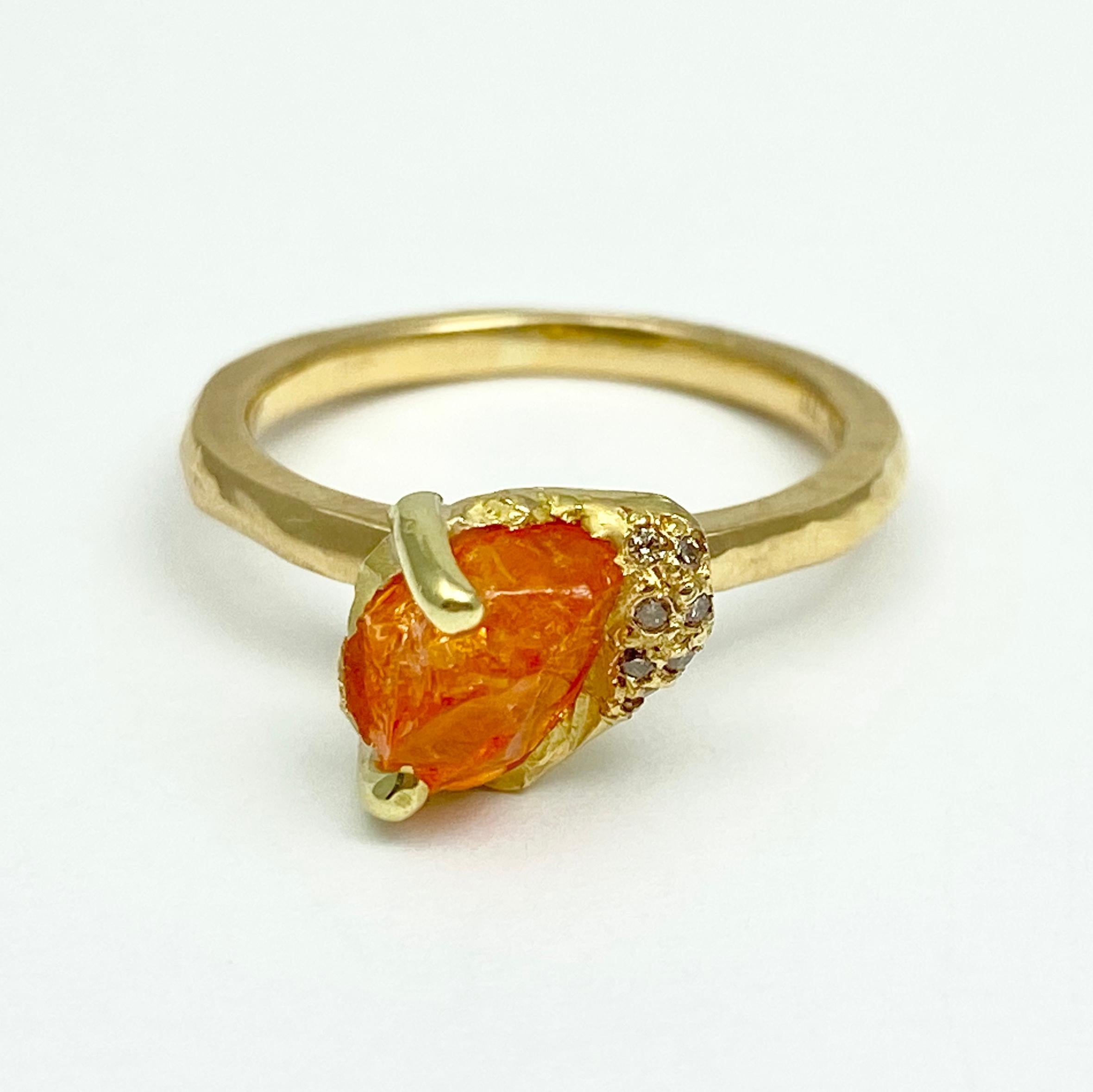 The Gee ring, from our Watu Collection, is hand-crafted with 18-karat recycled yellow gold, and features one untreated, Tenda Cut, natural orange color spessartine garnet (also called spessartite); and seven round champagne accent diamonds. Designed