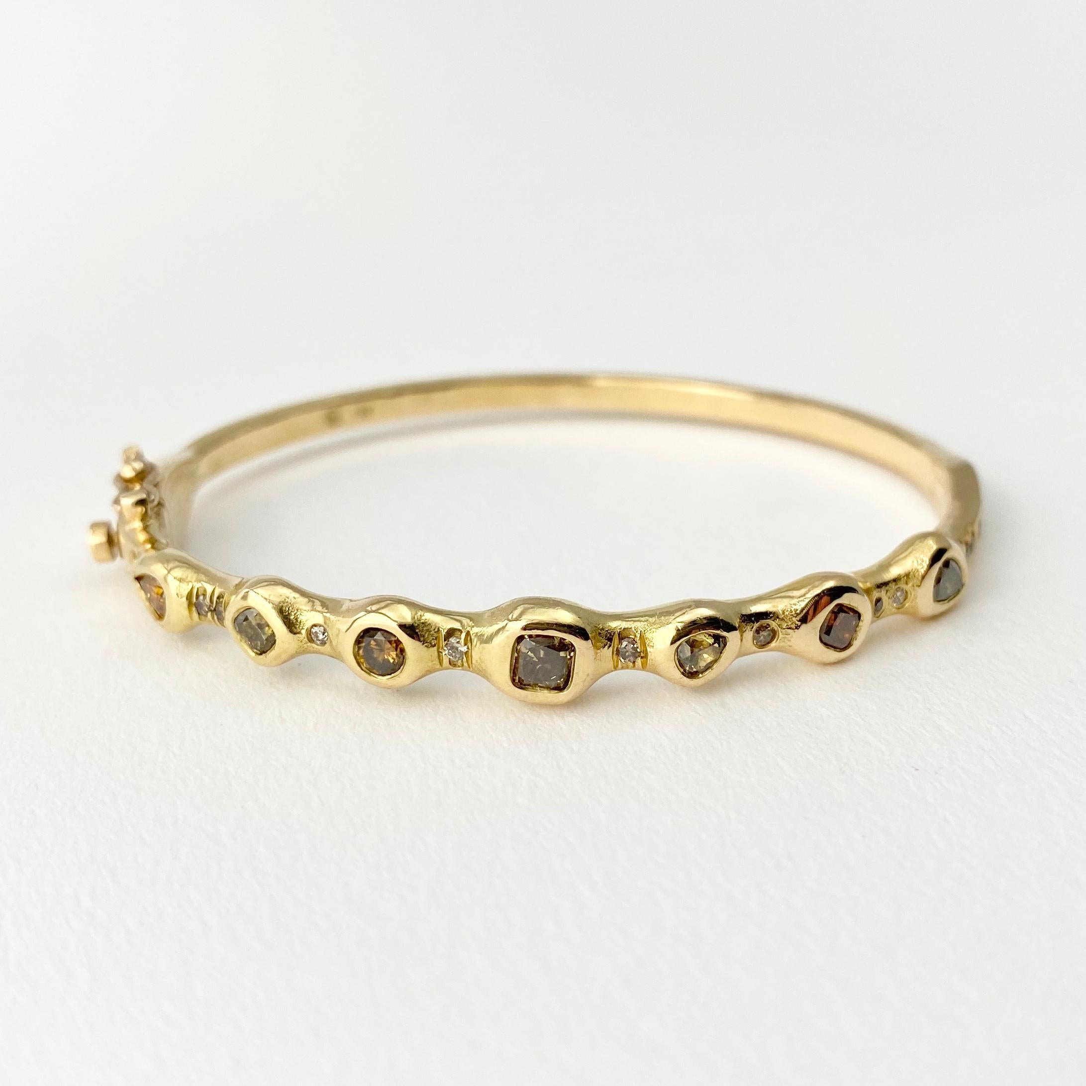 The Stepping Stone hinged bangle bracelet, from our Barefoot Collection, is hand-crafted with 18-karat recycled yellow gold, and features seven bezel set, colored diamonds in various sizes (three cushion shape, three pear, and one round); and 13