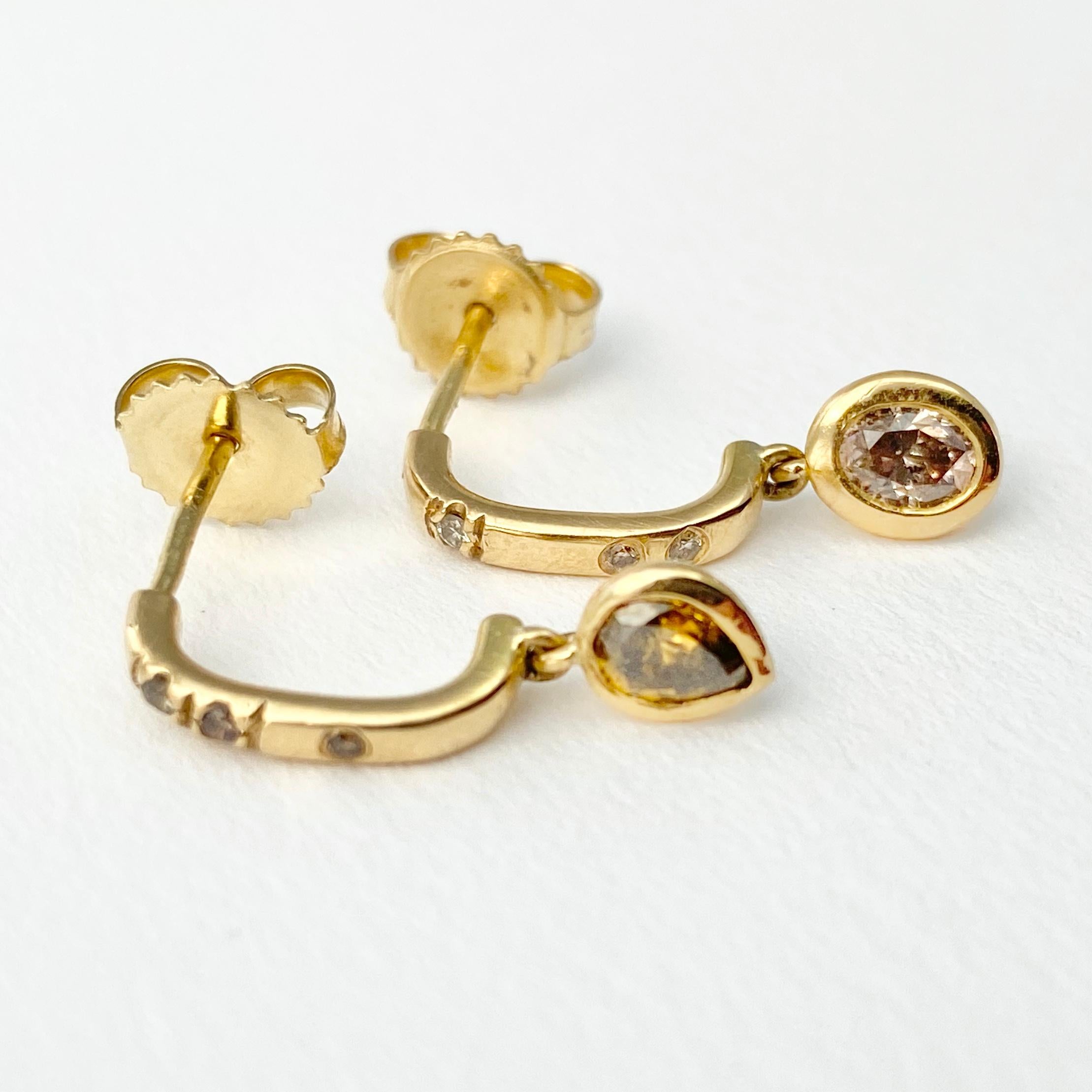 The Pebble half-hoop style drop earrings, from our Barefoot Collection, are crafted in 18-karat recycled yellow gold and feature two bezel set, colored diamonds (one oval shape, and one pear); and six round, champagne accent diamonds. The bezel-set