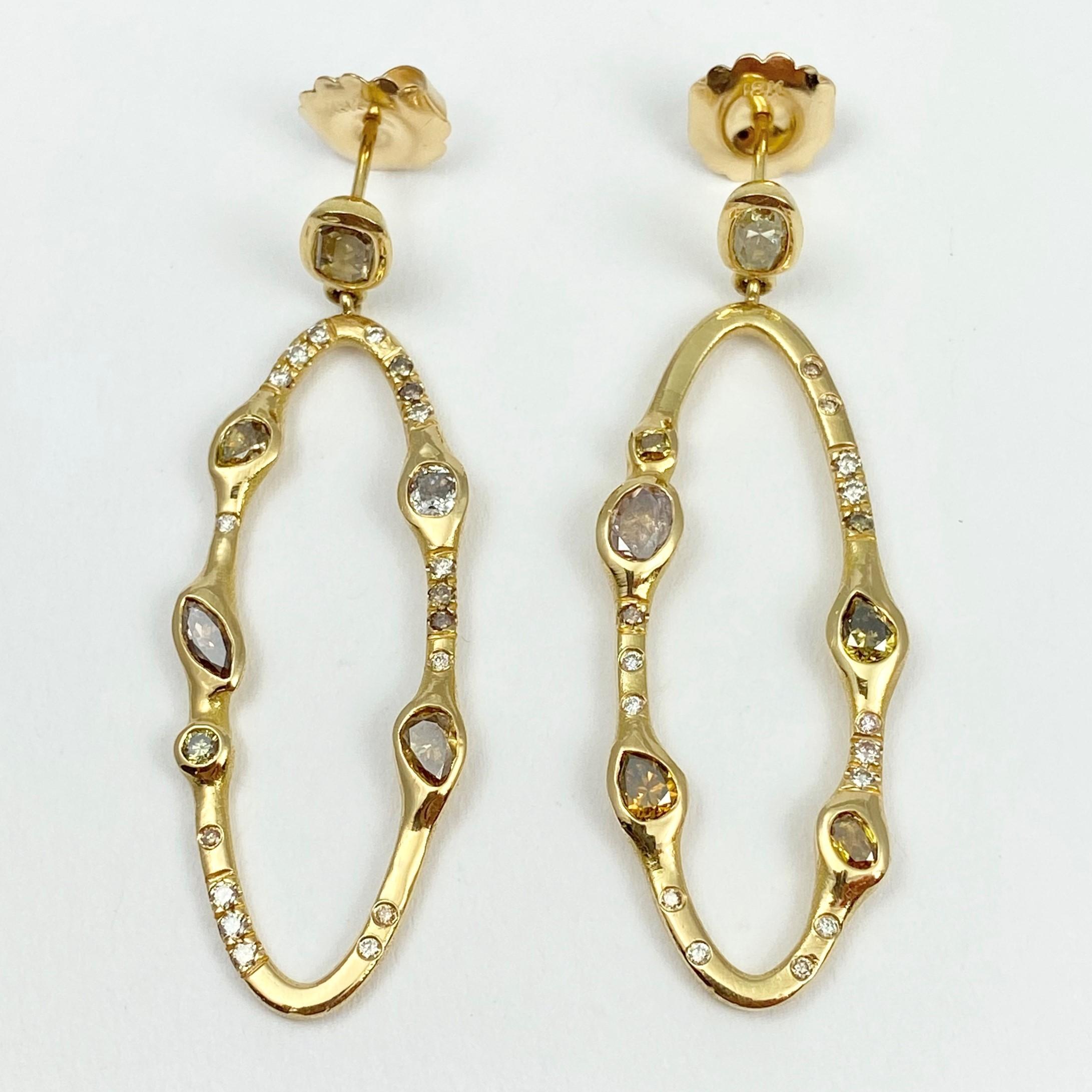 The larger size Pathway oval earrings are hand-crafted with 18-karat recycled yellow gold, and feature 12 bezel set, colored diamonds (four pear shape, three oval, two cushion, one marquise, one round, and one step-cut); and 33 round champagne