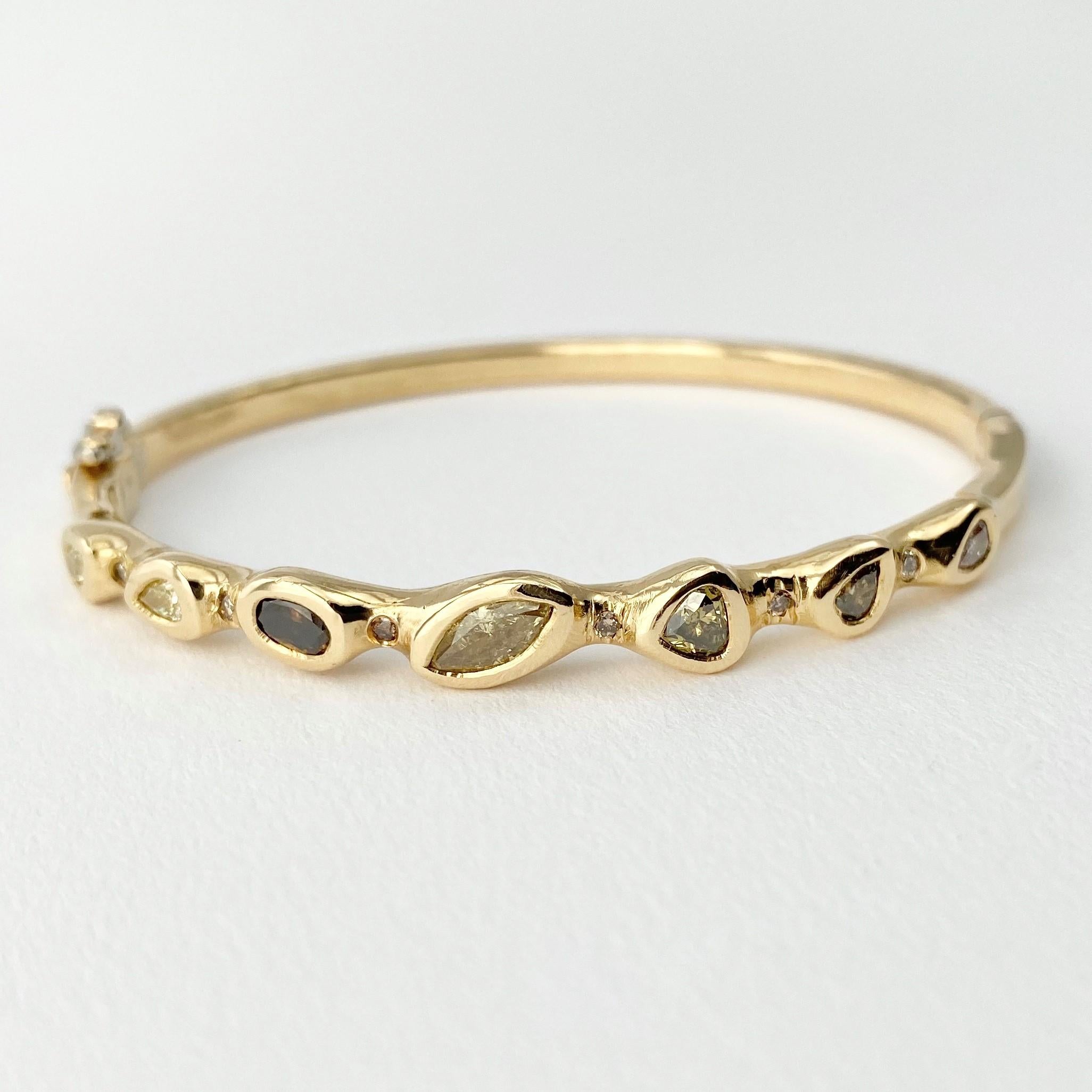 The Stepping Stone hinged bangle bracelet, from our Barefoot Collection, is hand-crafted with 18-karat recycled yellow gold, and features seven bezel set, colored diamonds (five pear shape, one marquise, and one oval) in various sizes; and six round