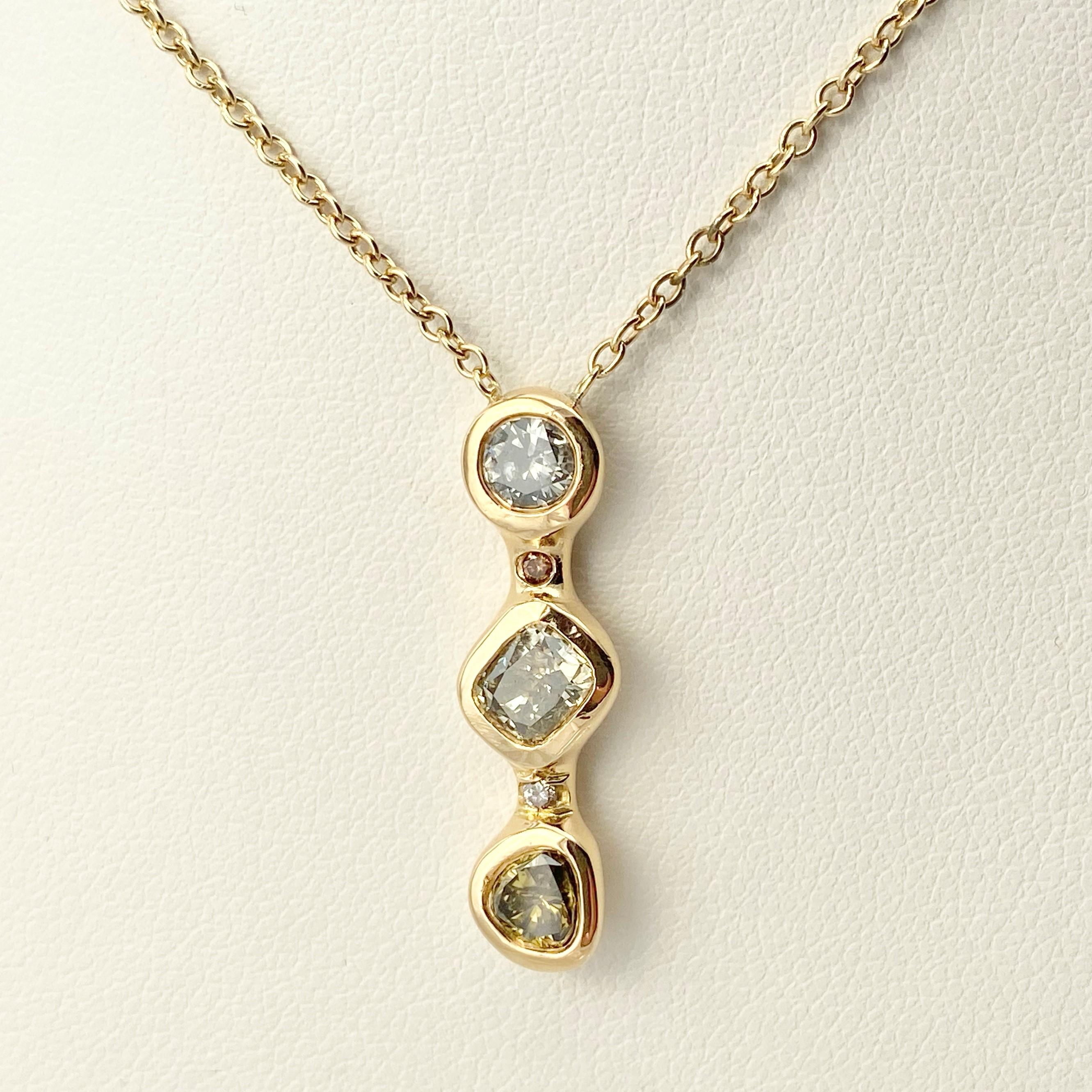 This Stepping Stone vertical three-diamond necklace is hand-made with 18 karat recycled yellow gold, and features three bezel set, natural color diamonds (one cushion shape, one pear, and one round); and two round champagne accent diamonds. The