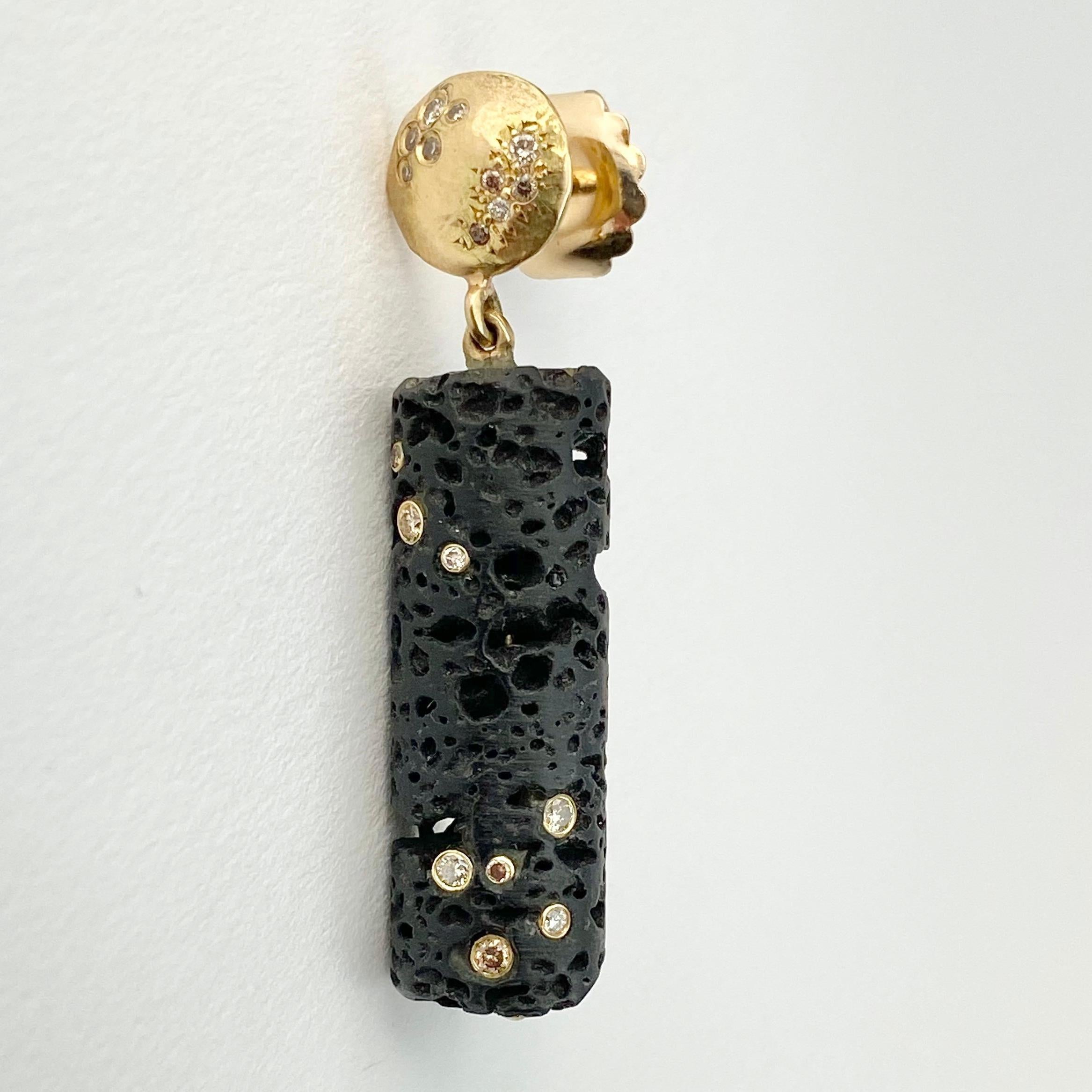 This pair of Lava Bead earrings is hand-crafted with 18-karat recycled yellow gold, and features two cylindrical black lava beads, and 36 round champagne accent diamonds- some flush mounted inside the natural indentions. The lava beads dangle from